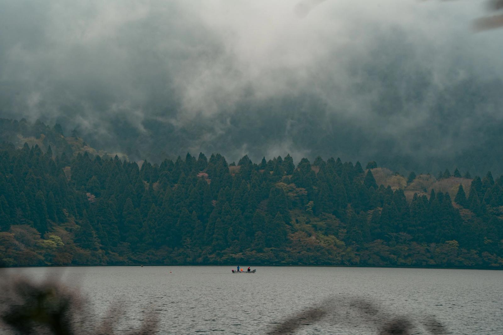 Serene view of Lake Ashi in Hakone, Japan with fog rolling over lush forests