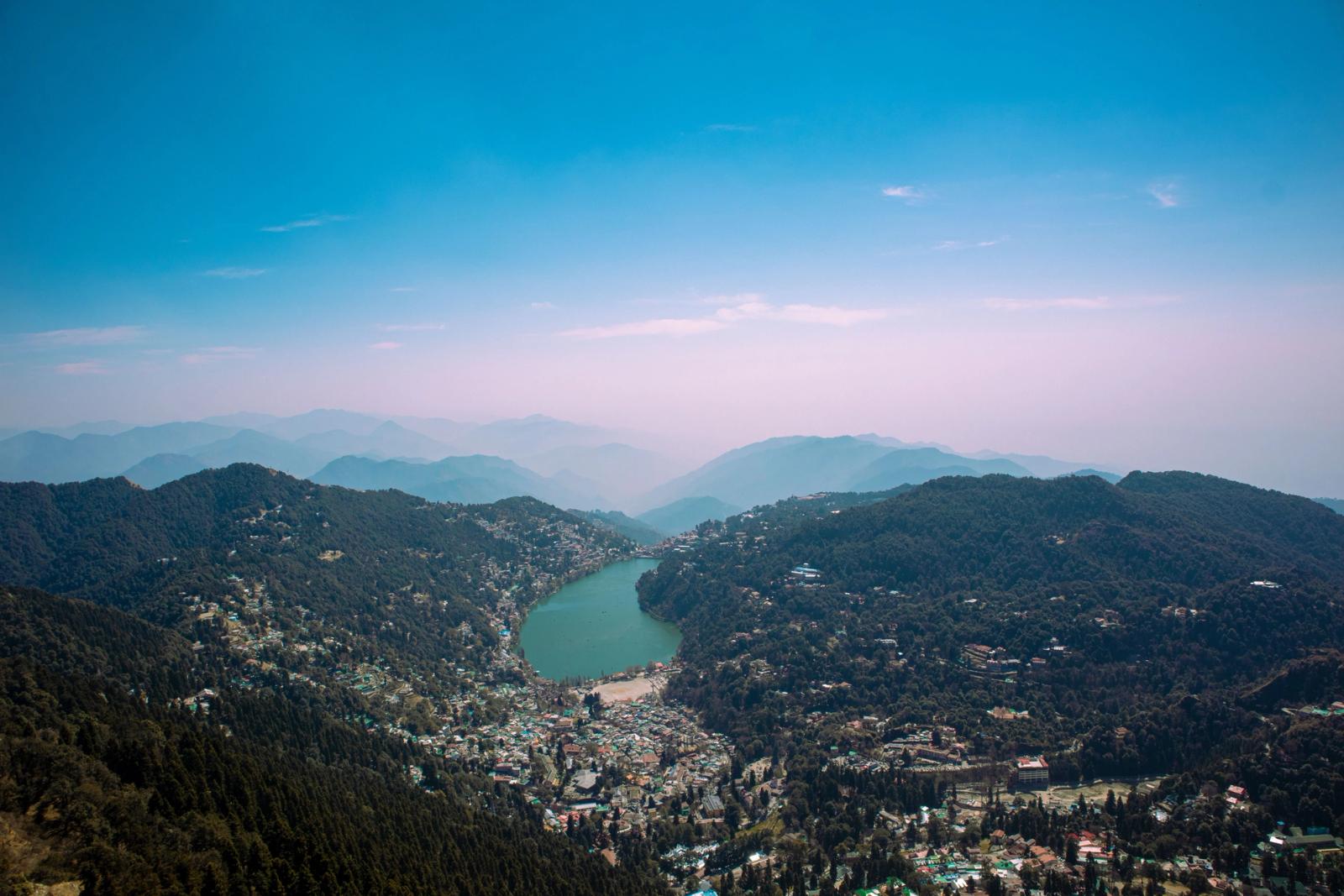 Aerial shot of Nainital Lake surrounded by lush forests and mountains in India