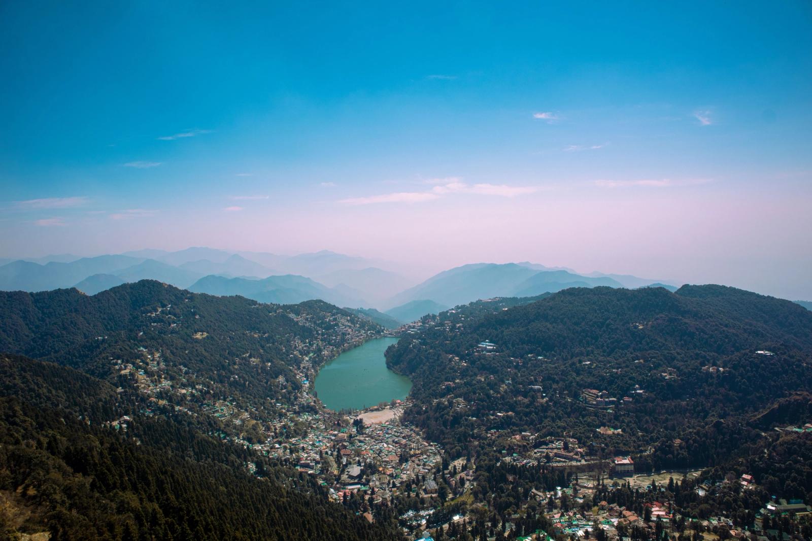 Aerial shot of Nainital Lake surrounded by lush forests and mountains in India