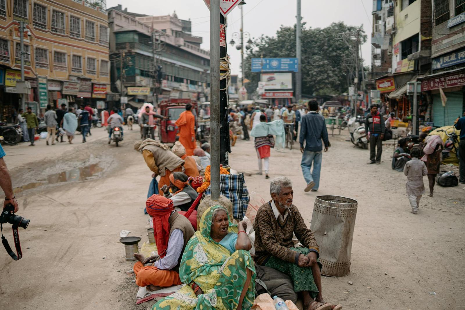 A busy street market with vendors and seated people along a dusty roadside