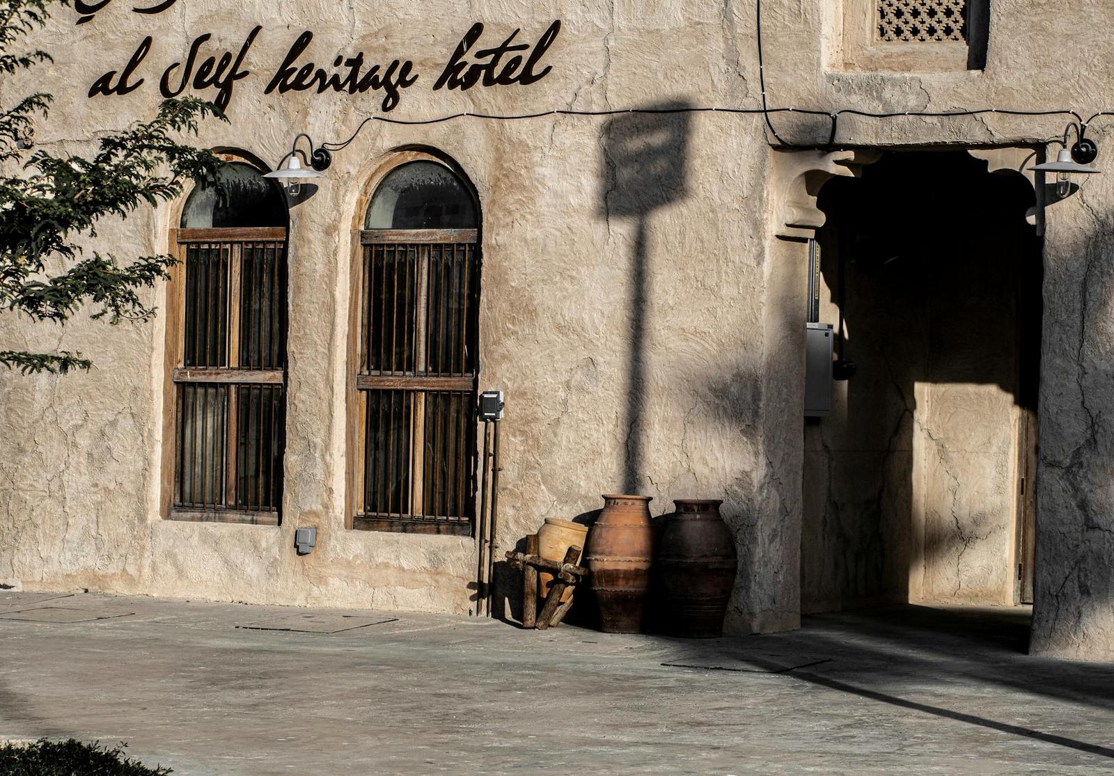 Heritage hotel entrance with arched shuttered windows and clay jars outside