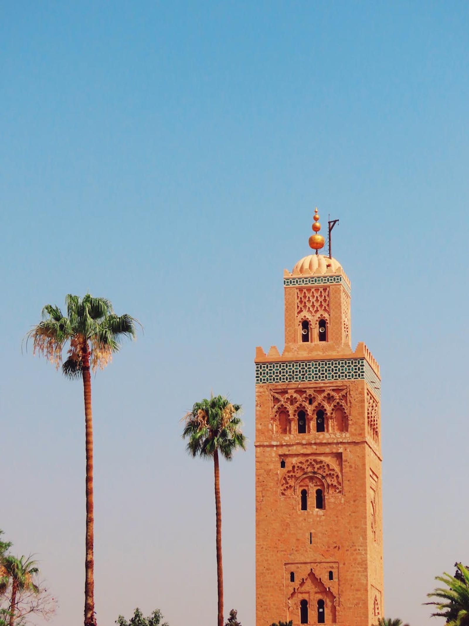 Iconic Koutoubia Mosque tower with palm trees in Marrakech against a clear blue sky