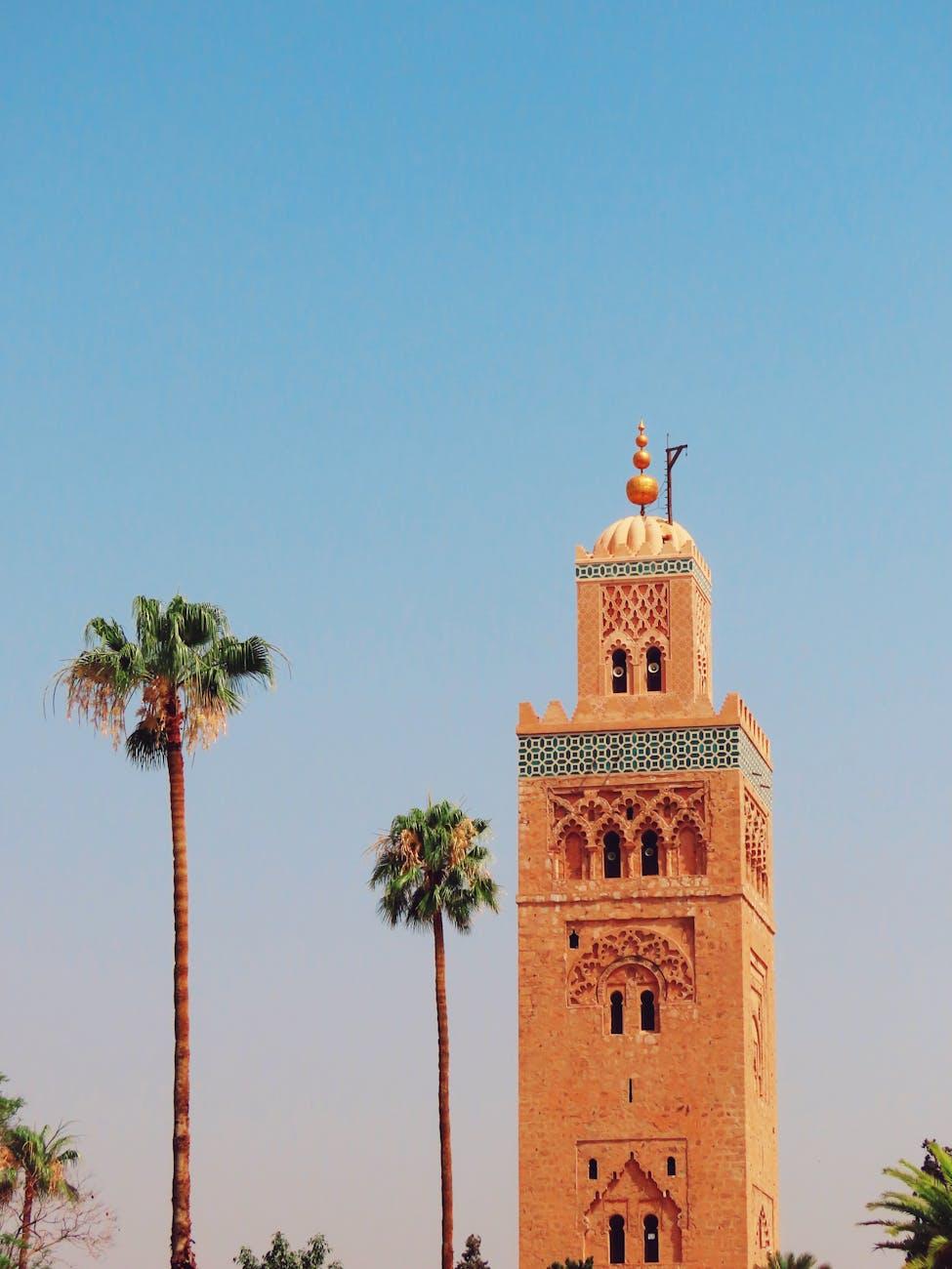 Iconic Koutoubia Mosque tower with palm trees in Marrakech against a clear blue sky