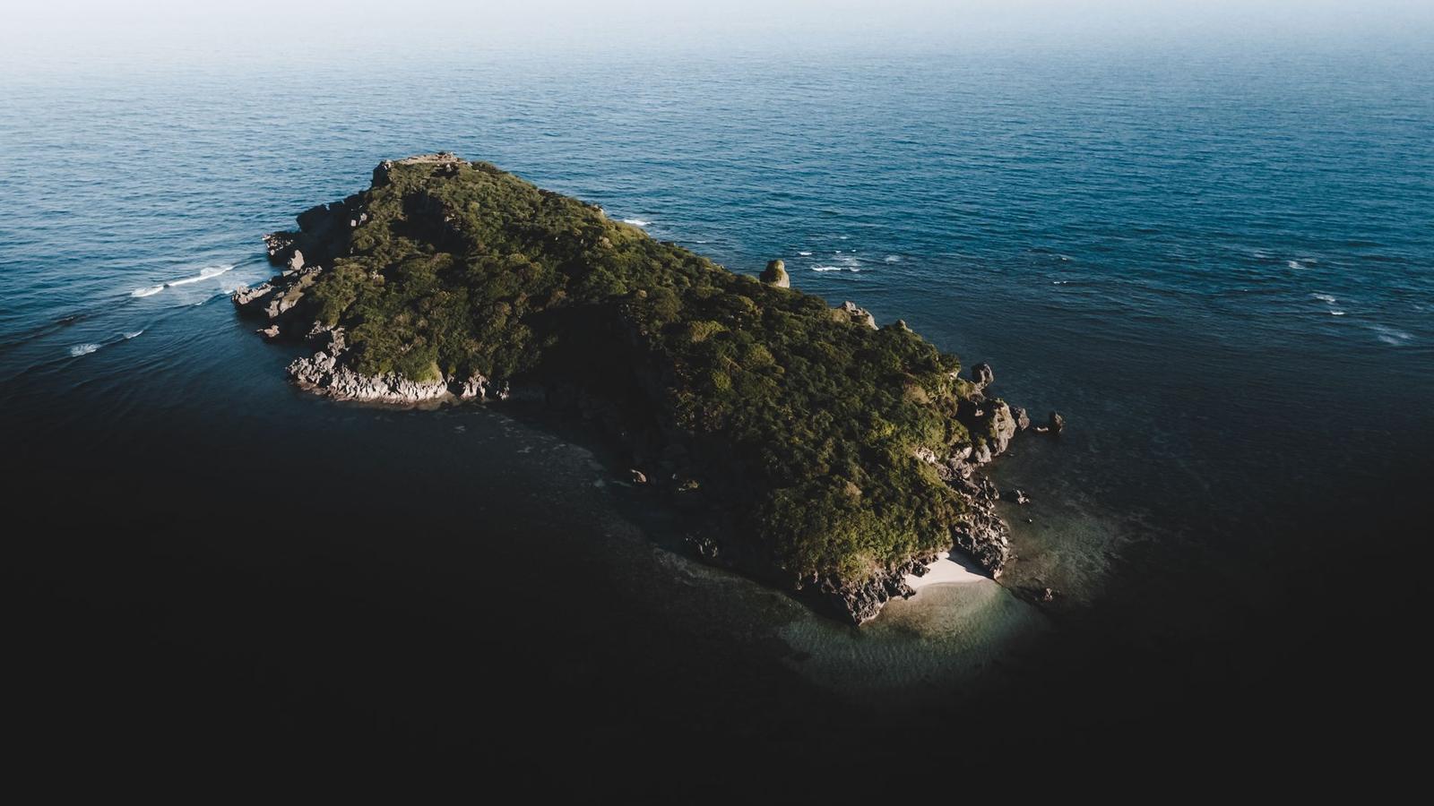 Aerial view of a small forested island surrounded by open sea