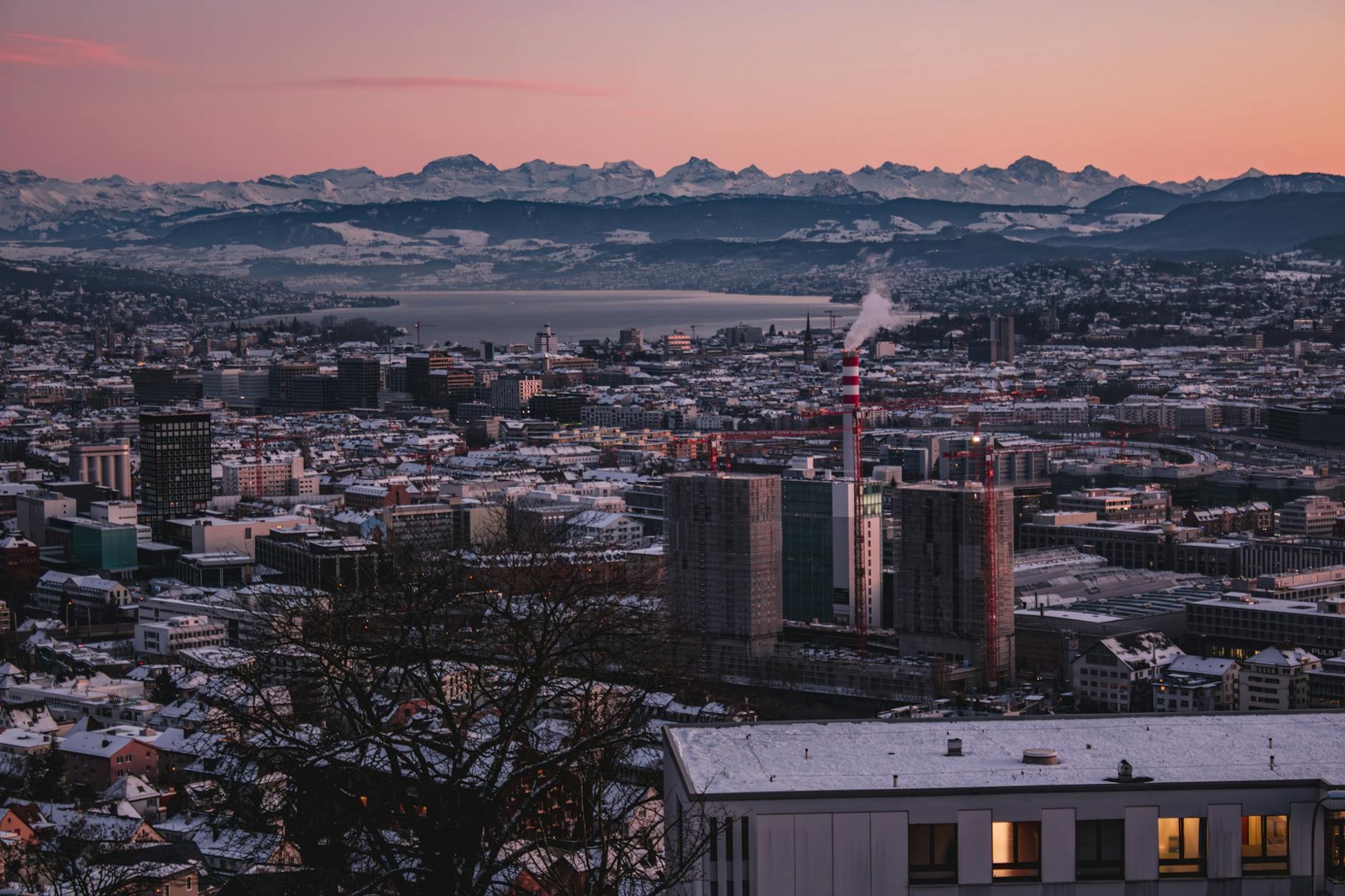 City skyline at dusk with snow-capped mountains on the horizon
