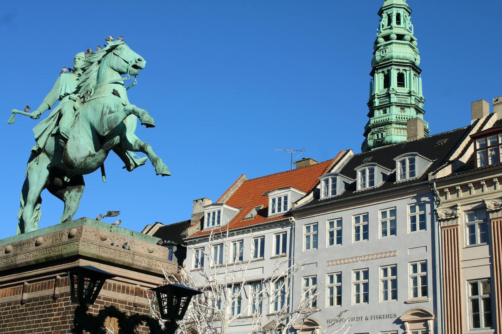 Embrace Copenhagen's historical architecture and sculptures under a bright blue sky