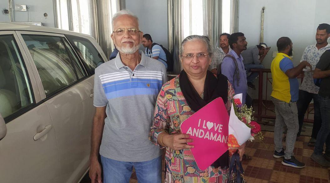 Old couple posing indoors holding an "I Love Andaman" sign.