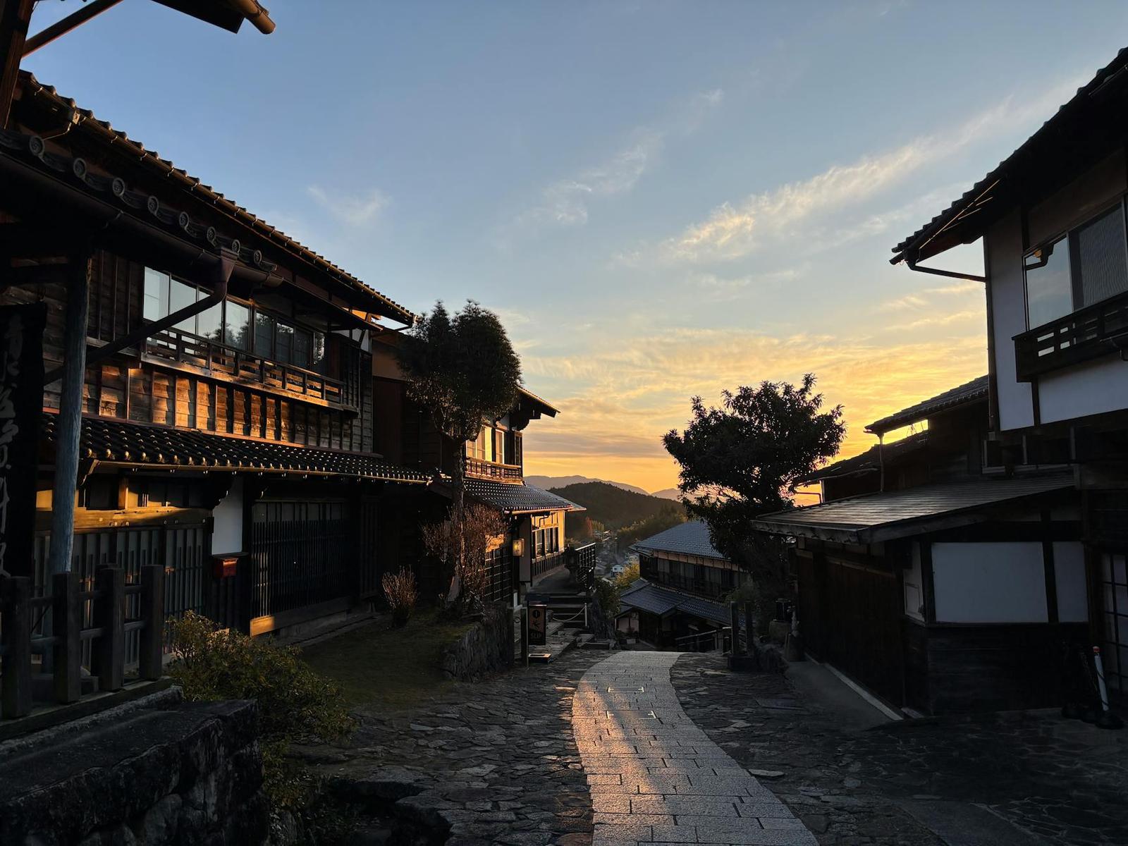 A stone-paved lane through a hillside village at golden hour