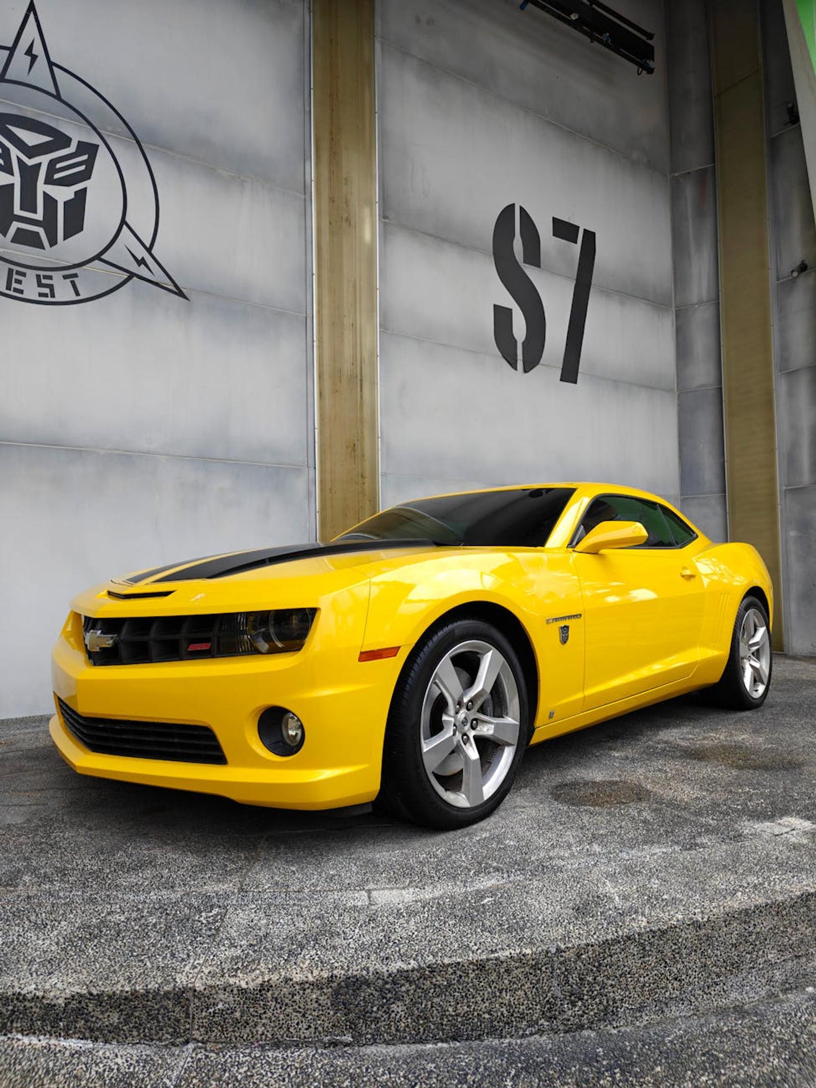 Yellow sports car parked beside a studio soundstage wall