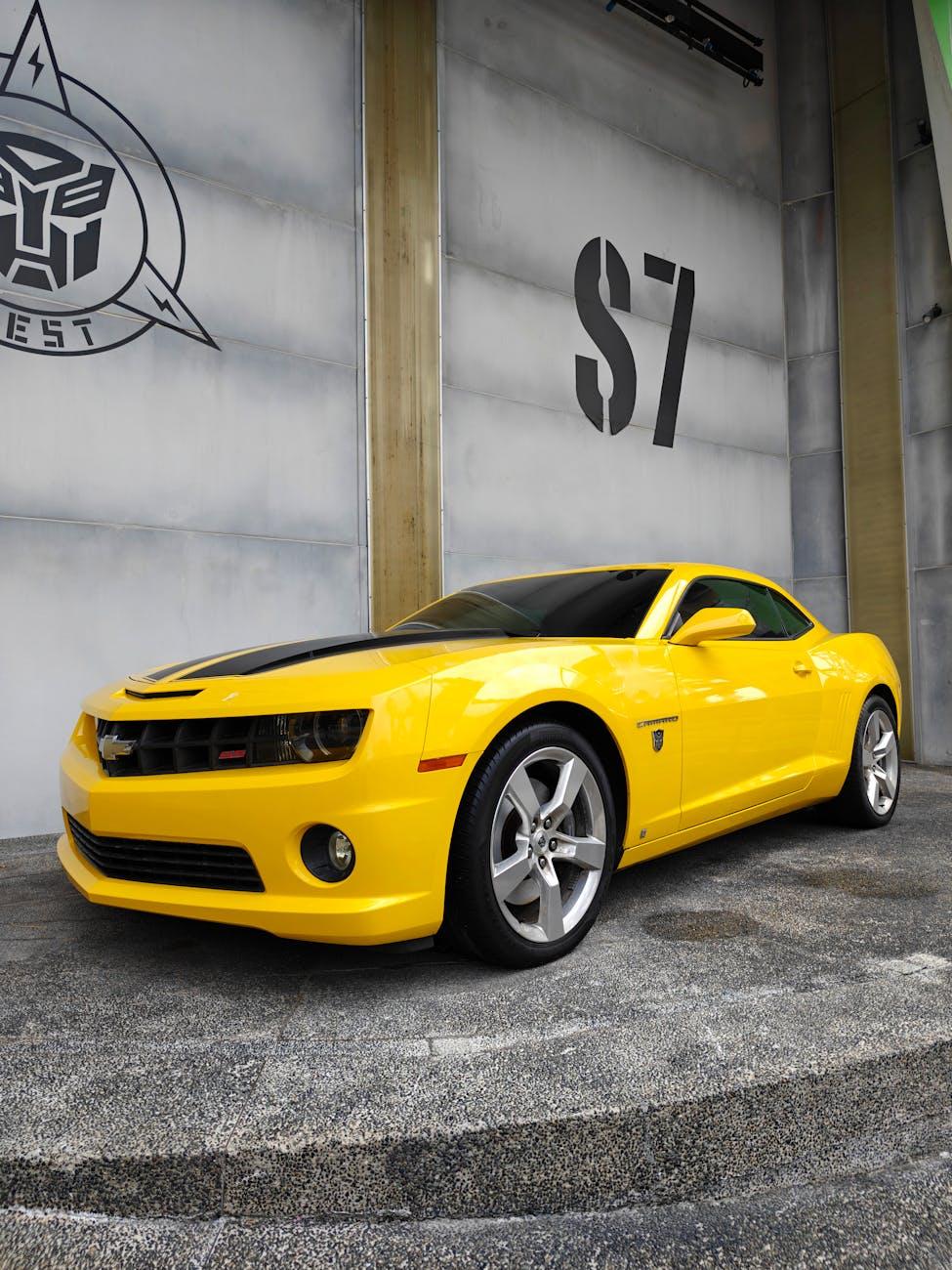 Yellow sports car parked beside a studio soundstage wall