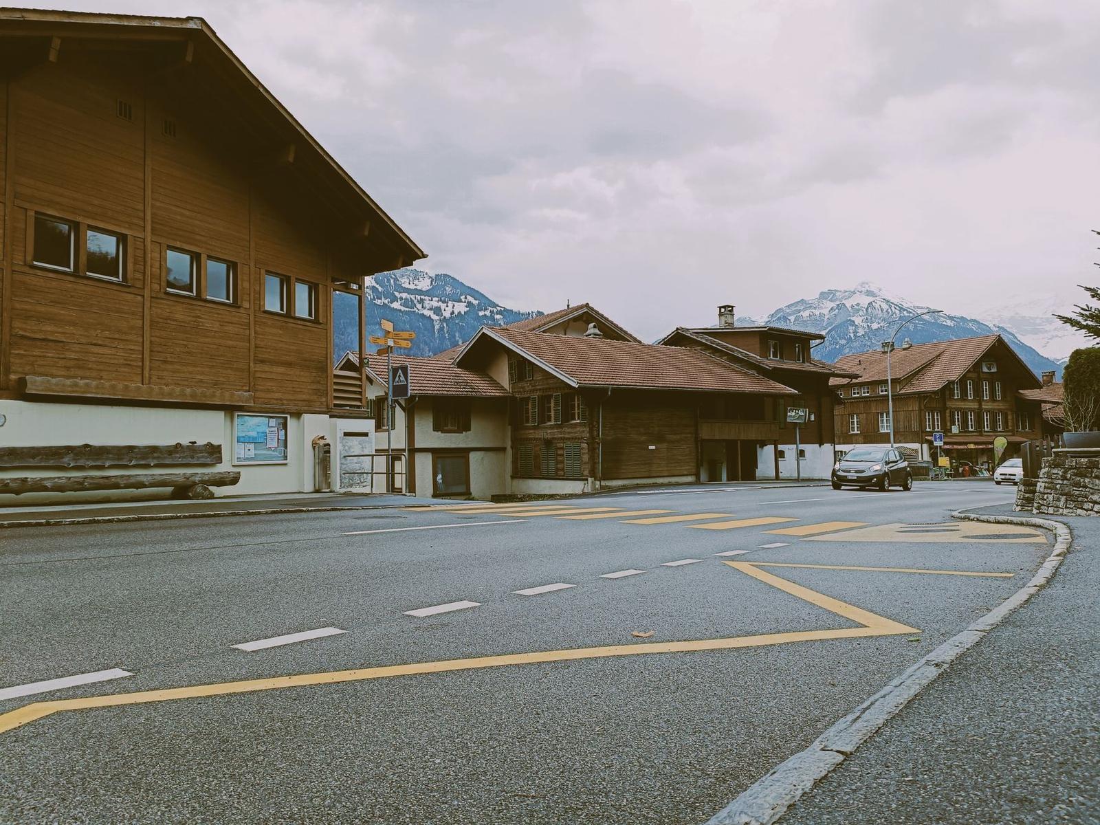 A quiet alpine village crossroads with wooden chalets and mountains in the background