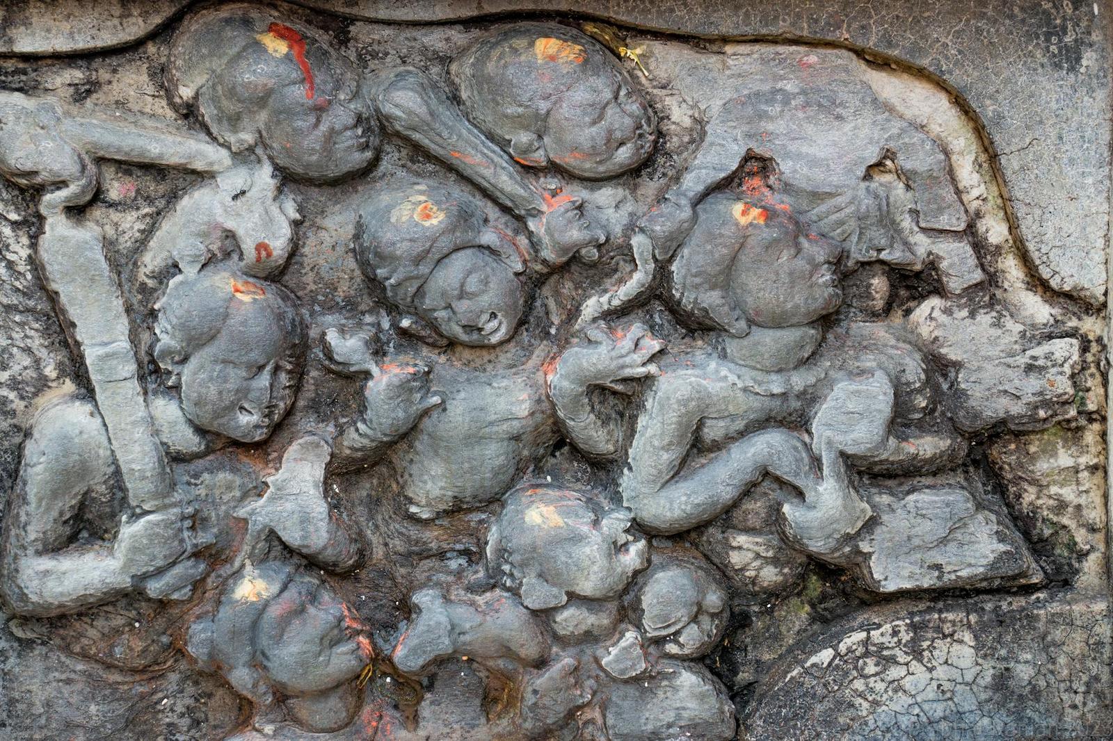 Close-up of a weathered stone relief carved with clustered figures