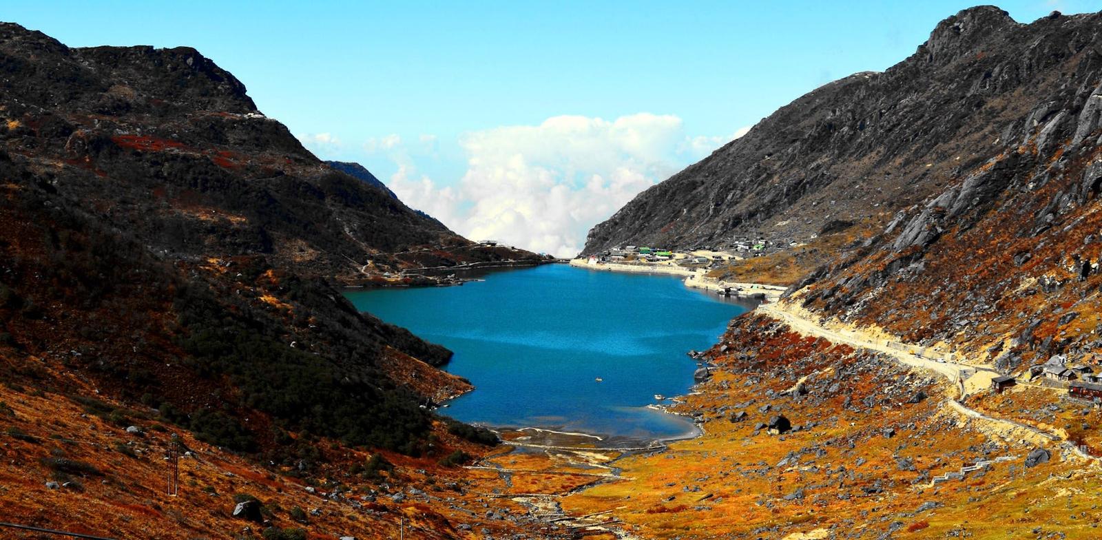A turquoise alpine lake nestled between rocky ridges with a road winding alongside