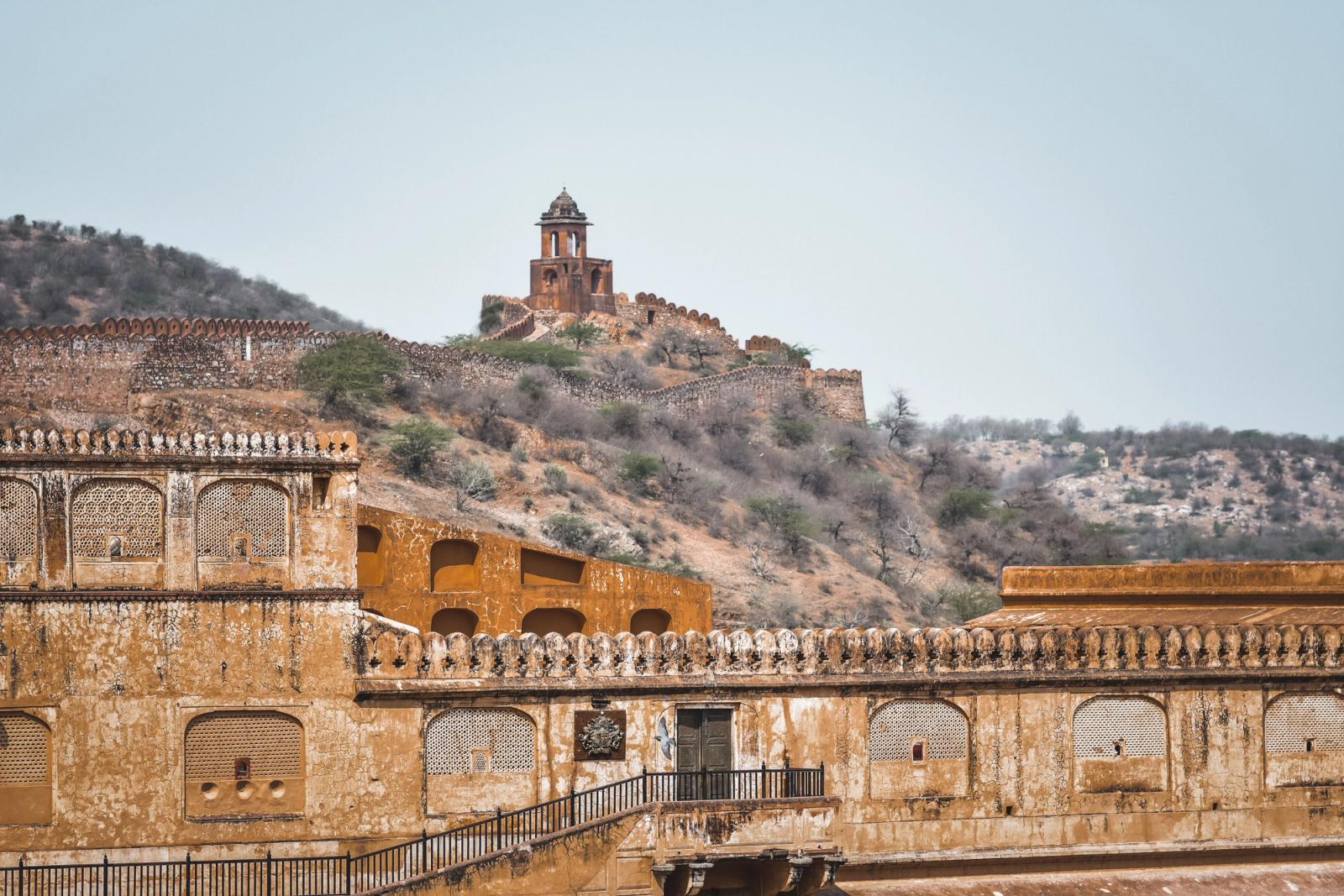 A hilltop watchtower rising above a weathered sandstone fort wall
