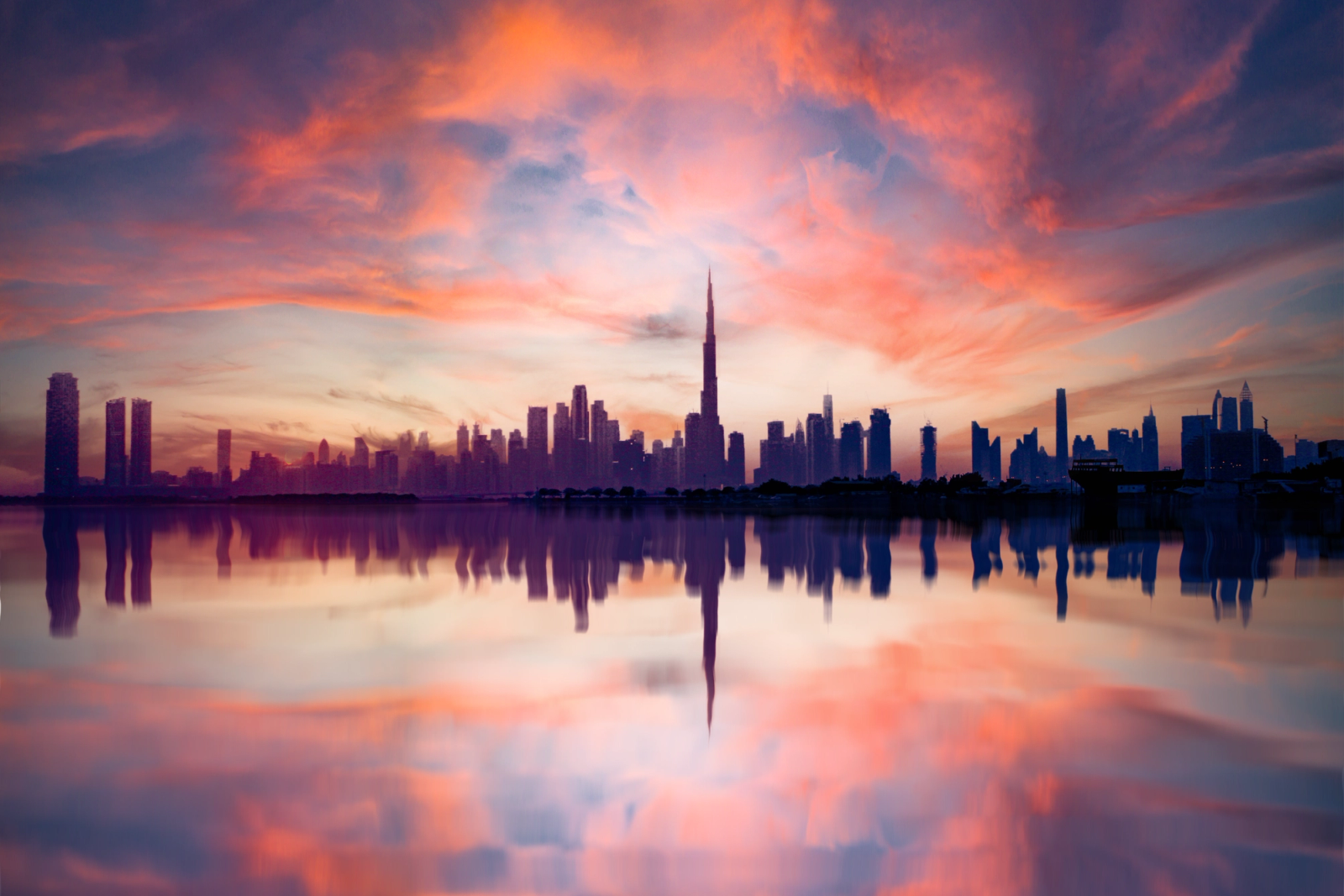 A breathtaking view of Dubai's skyline reflected in water during a vivid sunset, highlighting the urban architecture