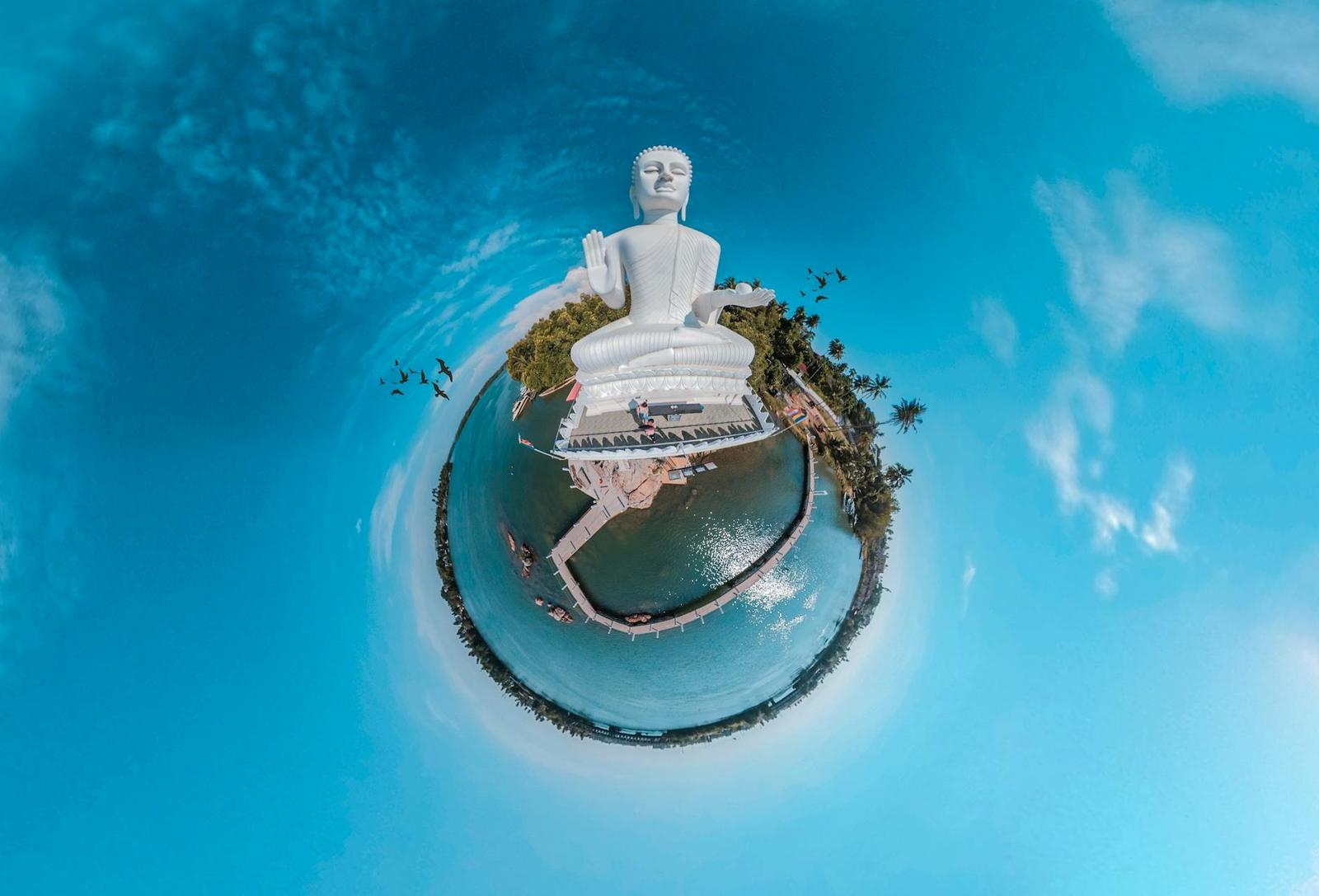 Tiny planet view of a Buddha statue surrounded by water and palm trees in Sri Lanka