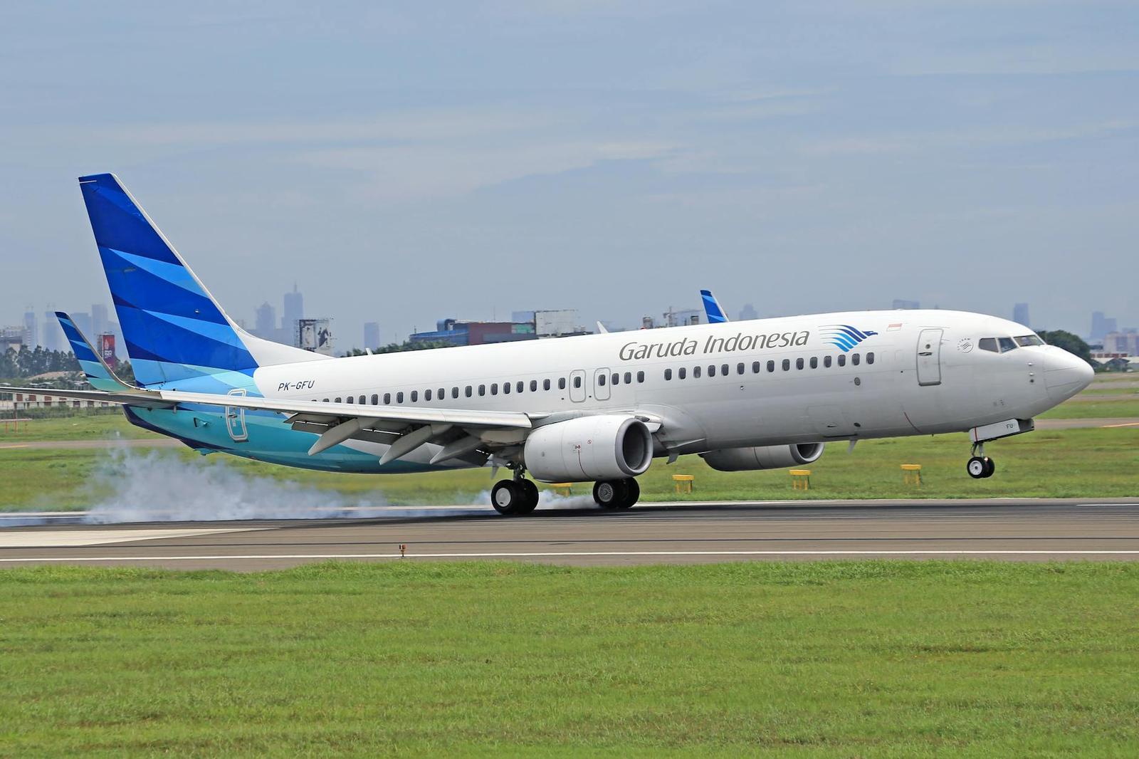 A passenger jet takes off with a hazy city skyline in the background