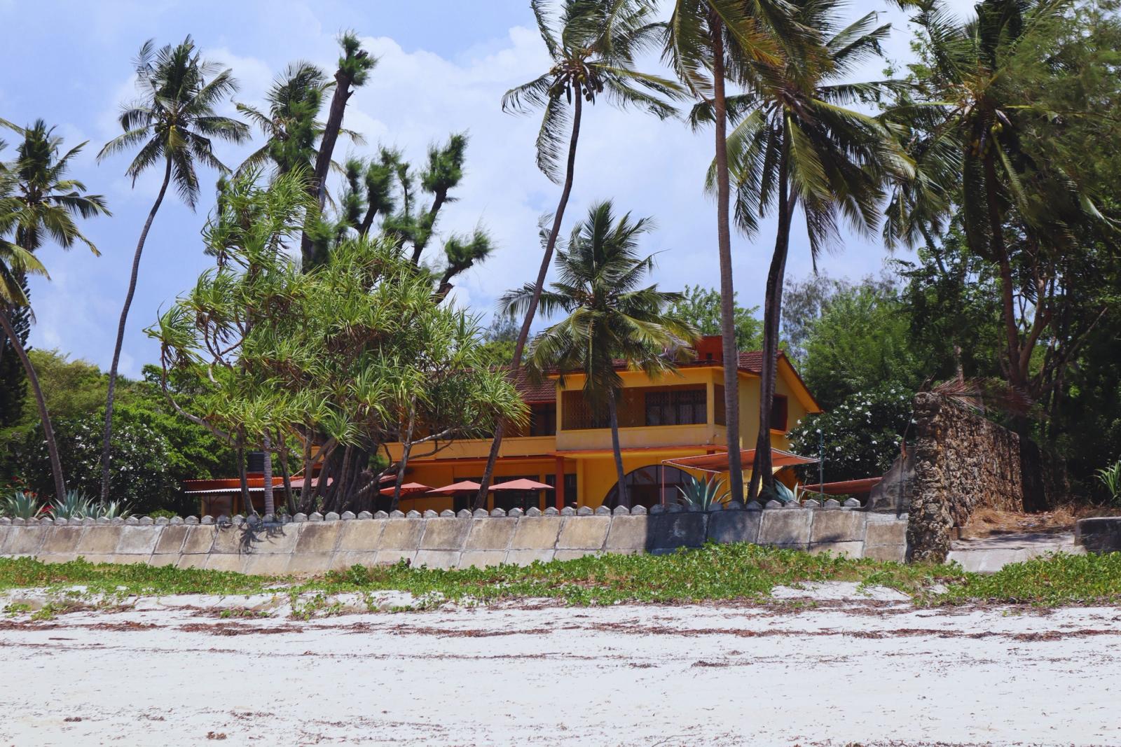 A serene beachfront house in Mombasa, Kenya, surrounded by palm trees and lush greenery