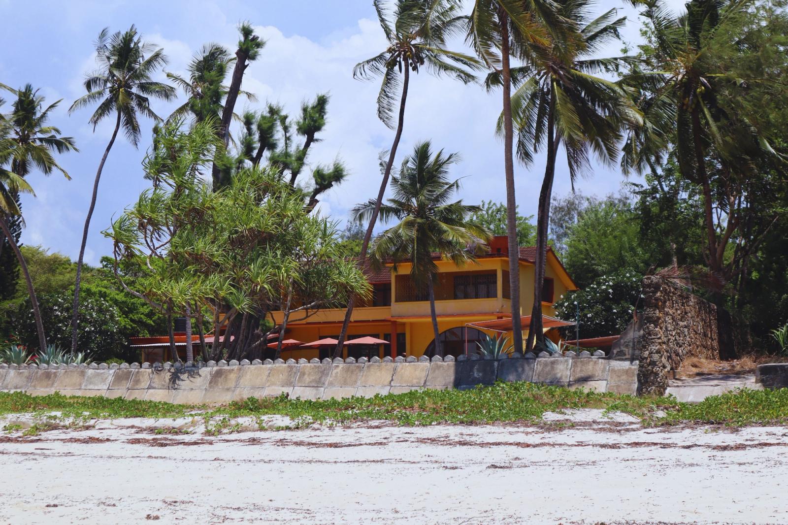 A serene beachfront house in Mombasa, Kenya, surrounded by palm trees and lush greenery