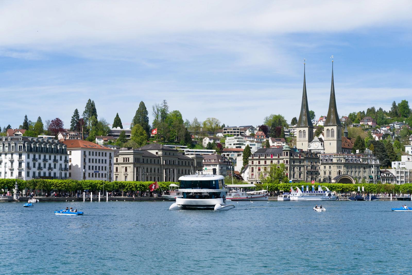 Picturesque view of Luzern with lake and boats, highlighting city architecture and Chapel Bridge