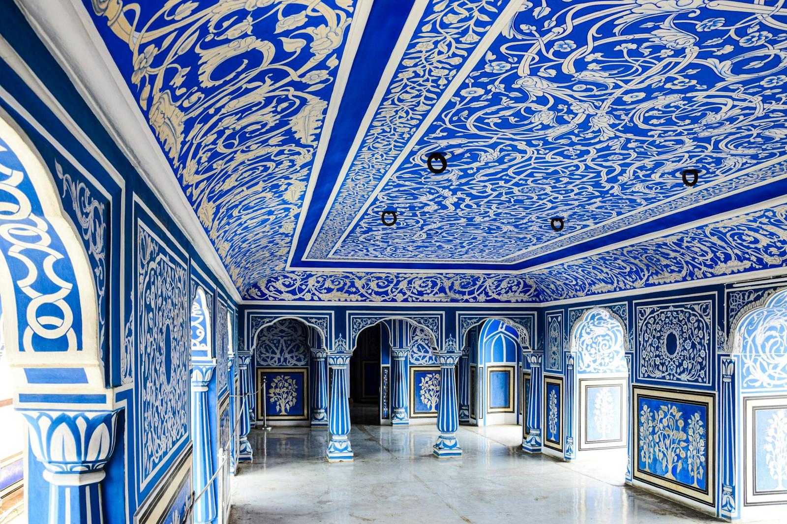 A blue and white painted courtyard with intricately patterned ceilings