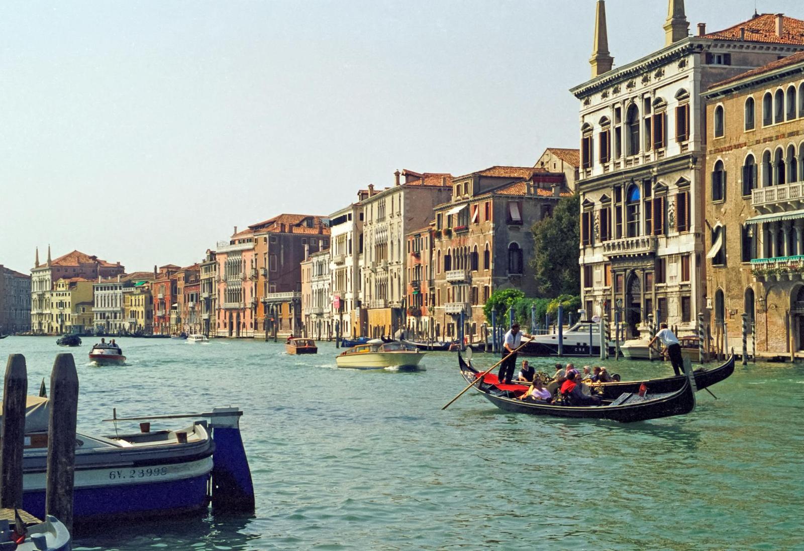 A gondola with passengers gliding down a grand canal lined with historic palazzos