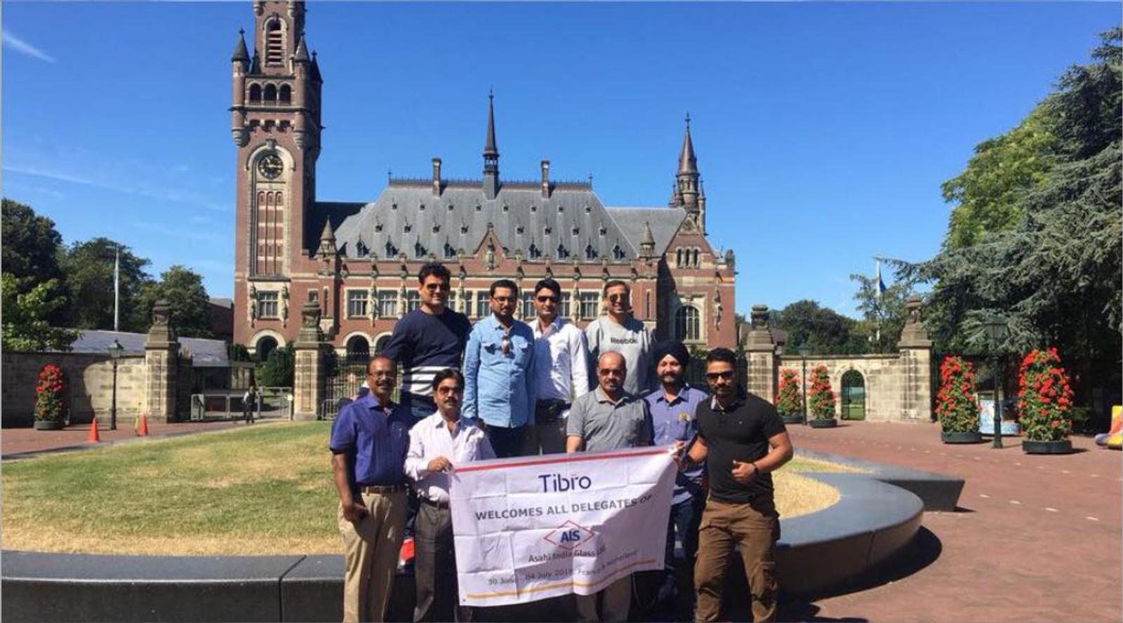 A group of men posing with a banner in front of a historic building.