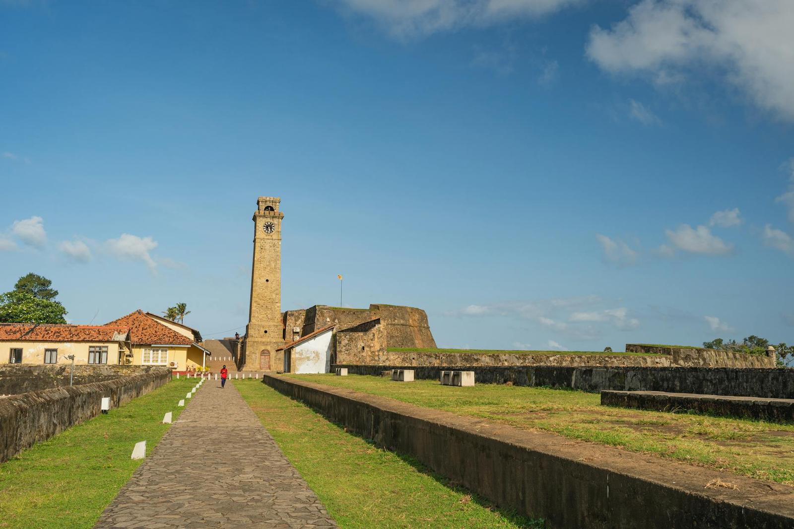 Fort clock tower with a lone visitor walking the cobbled path