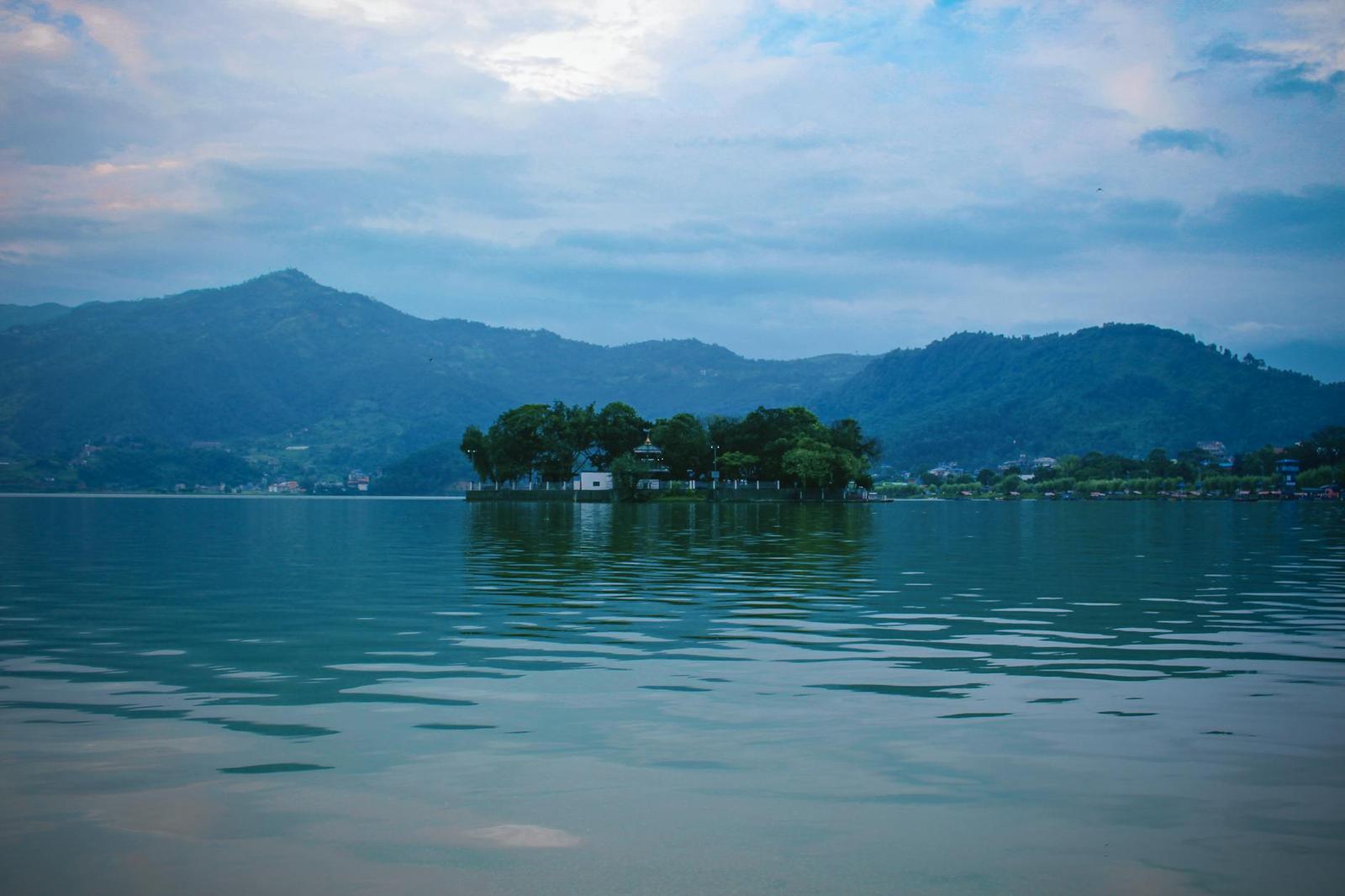 A small tree-covered island reflected in a still mountain lake