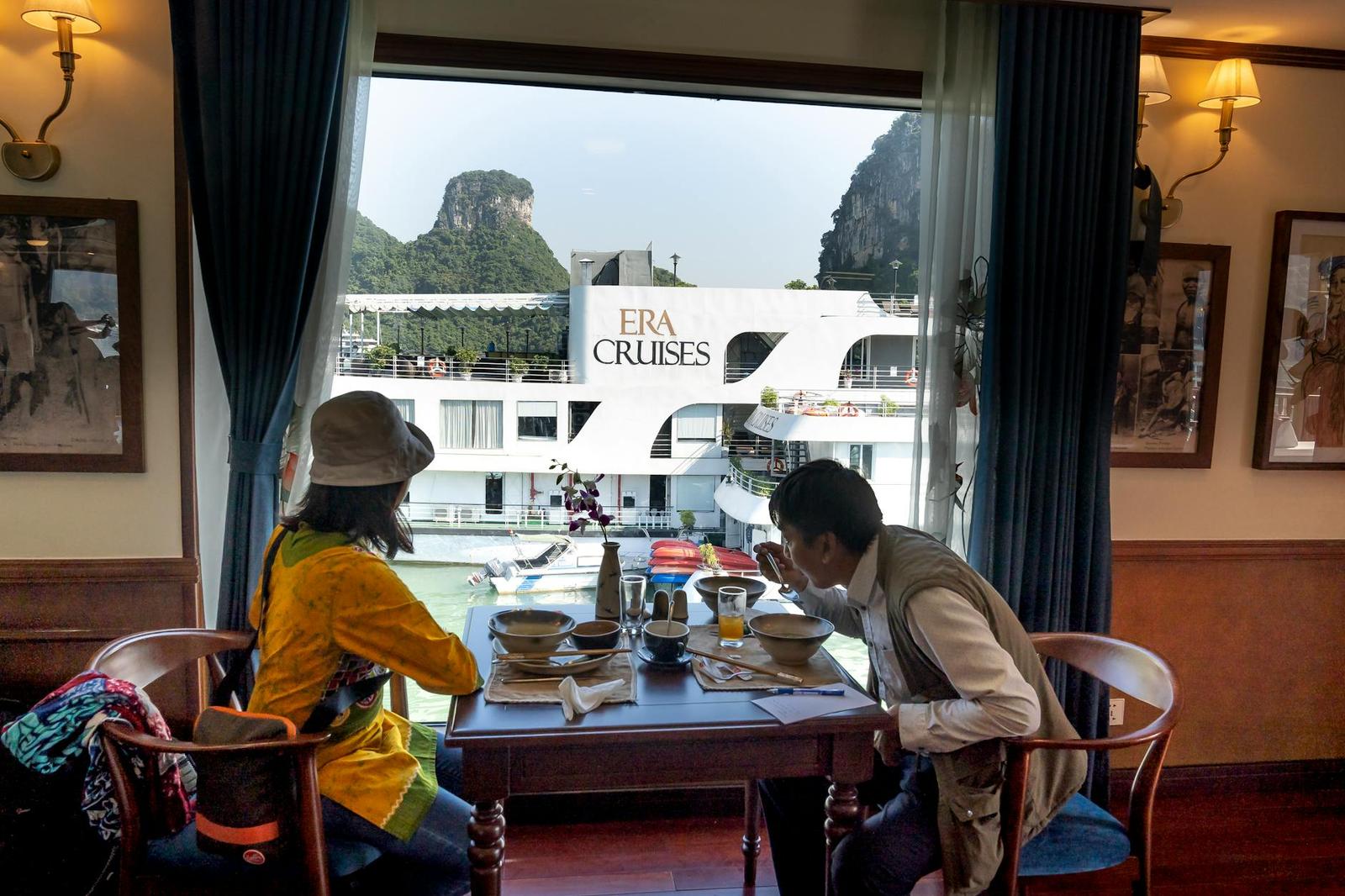 Side view of ethnic male tourist eating soup against unrecognizable female beloved at table on motorboat during cruise