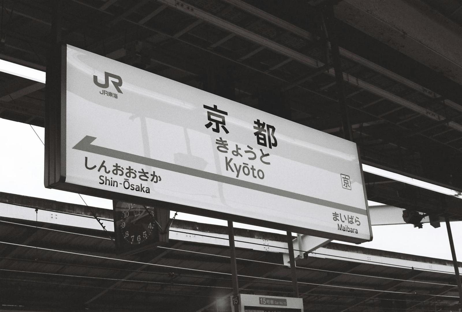 Railway platform signboard displaying Kyoto in Japanese and English with directions
