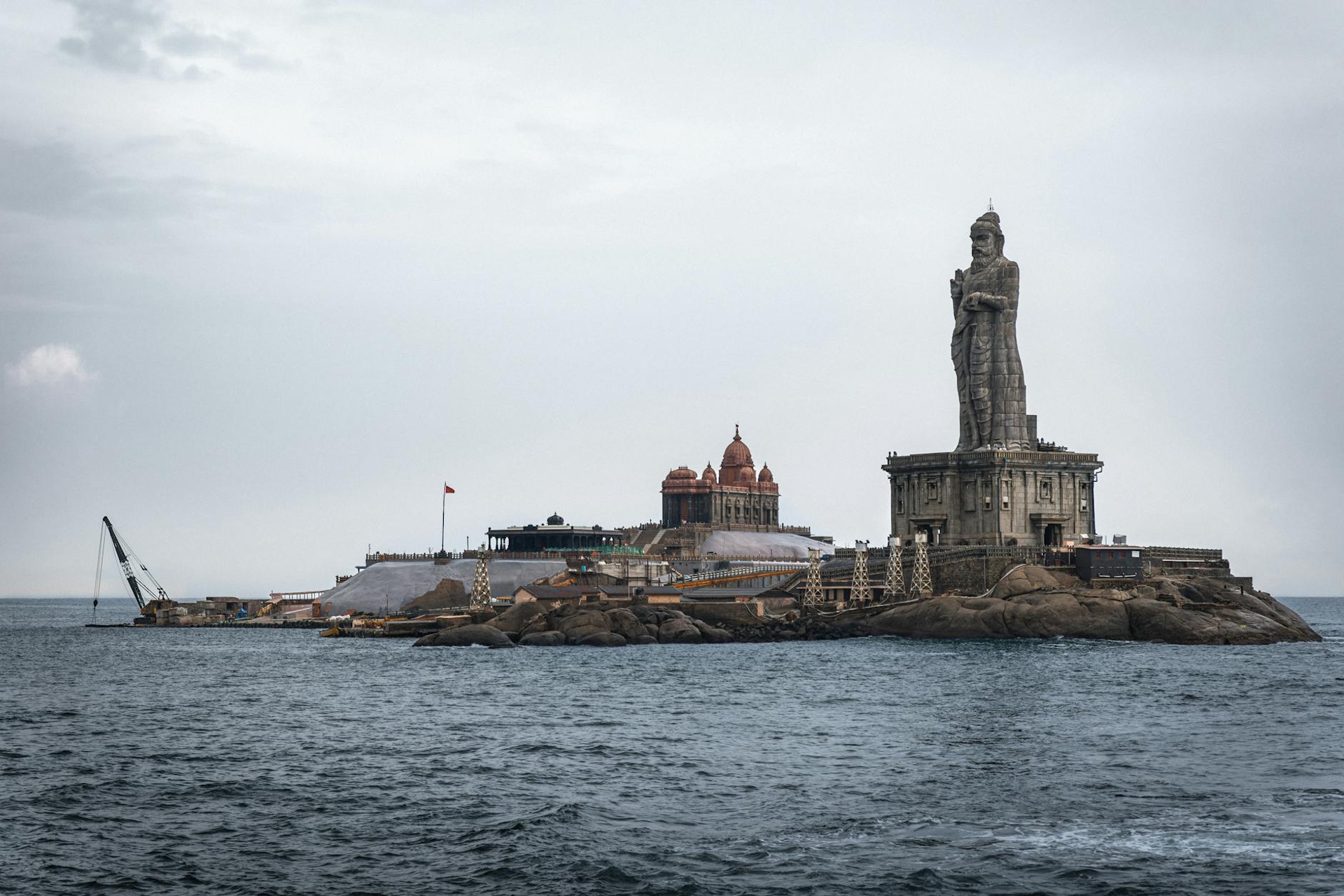 Large stone statue rising from a rocky island memorial in the sea