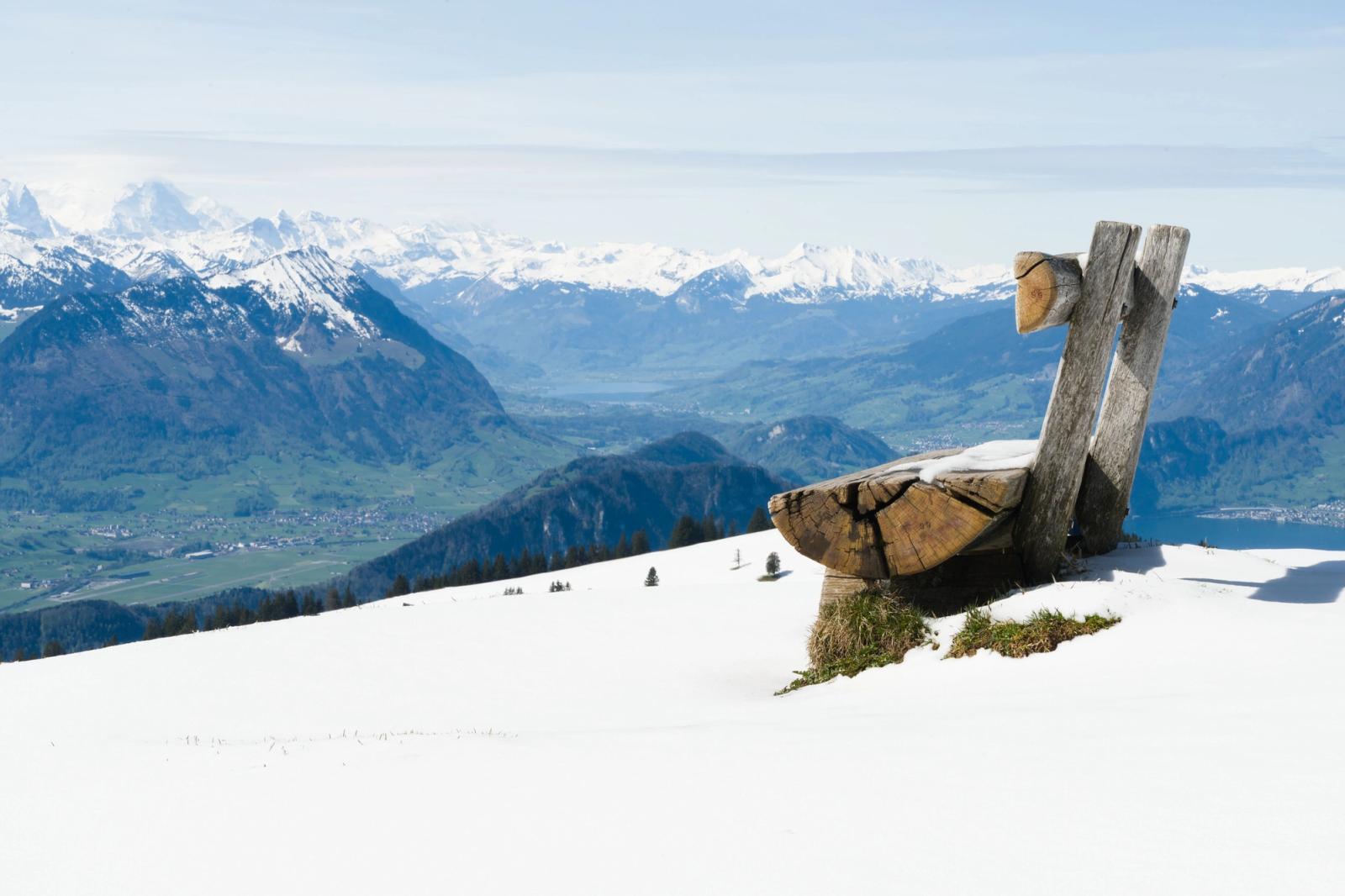 Wooden bench on snow-covered Rigi Mountain in Switzerland, offering panoramic views of the Alps