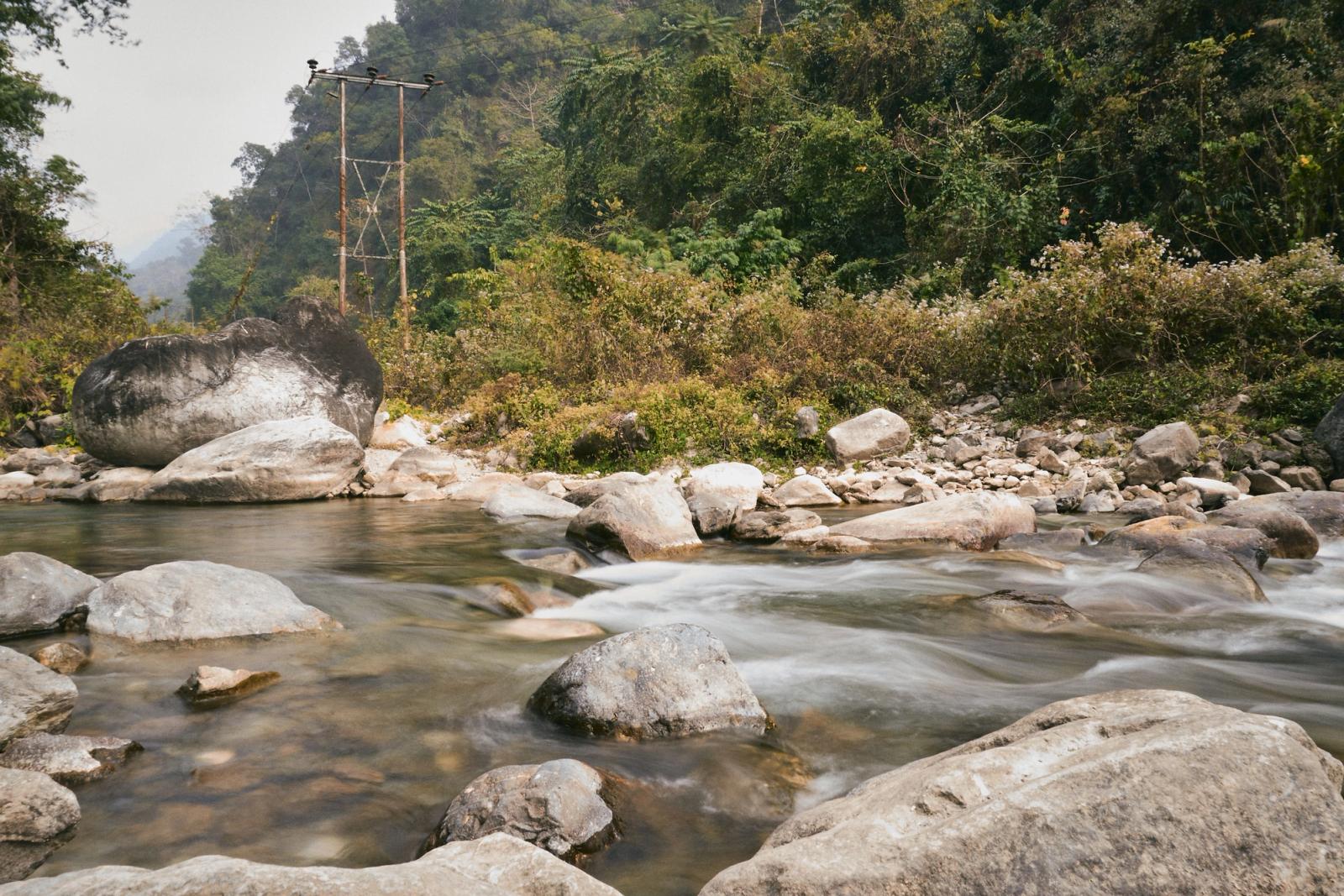 Discover the tranquility of a flowing stream amidst lush greenery in Panbang, Bhutan