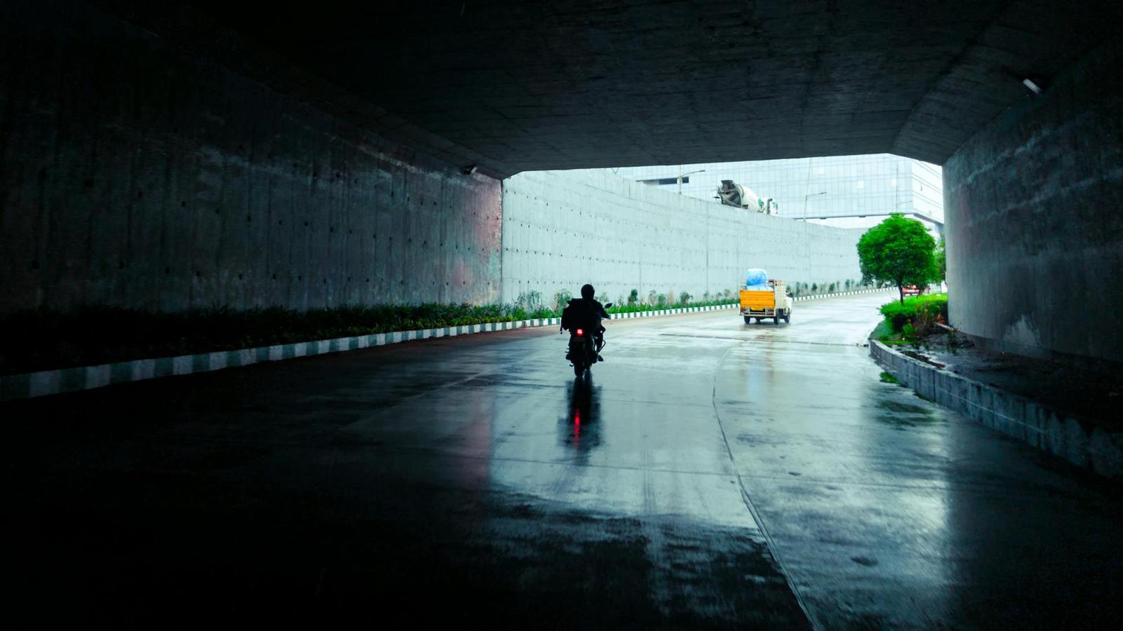 A motorcyclist riding through a wet underpass in the rain