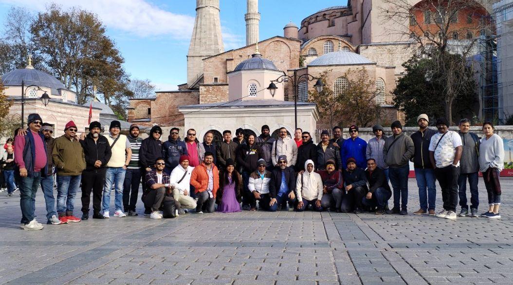 Group posing in front of a historic building with domes and minarets