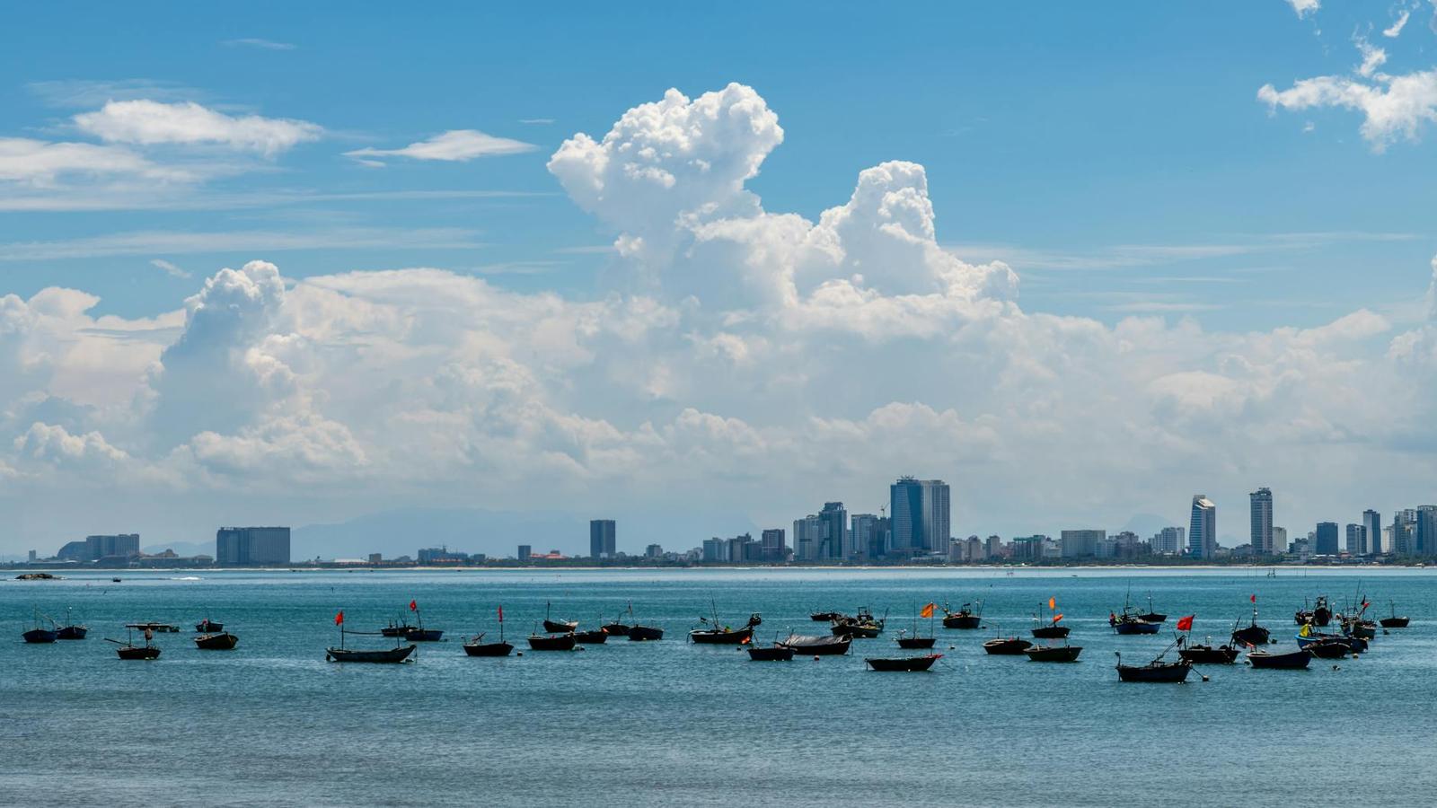 Small fishing boats anchored offshore with a city skyline on the horizon