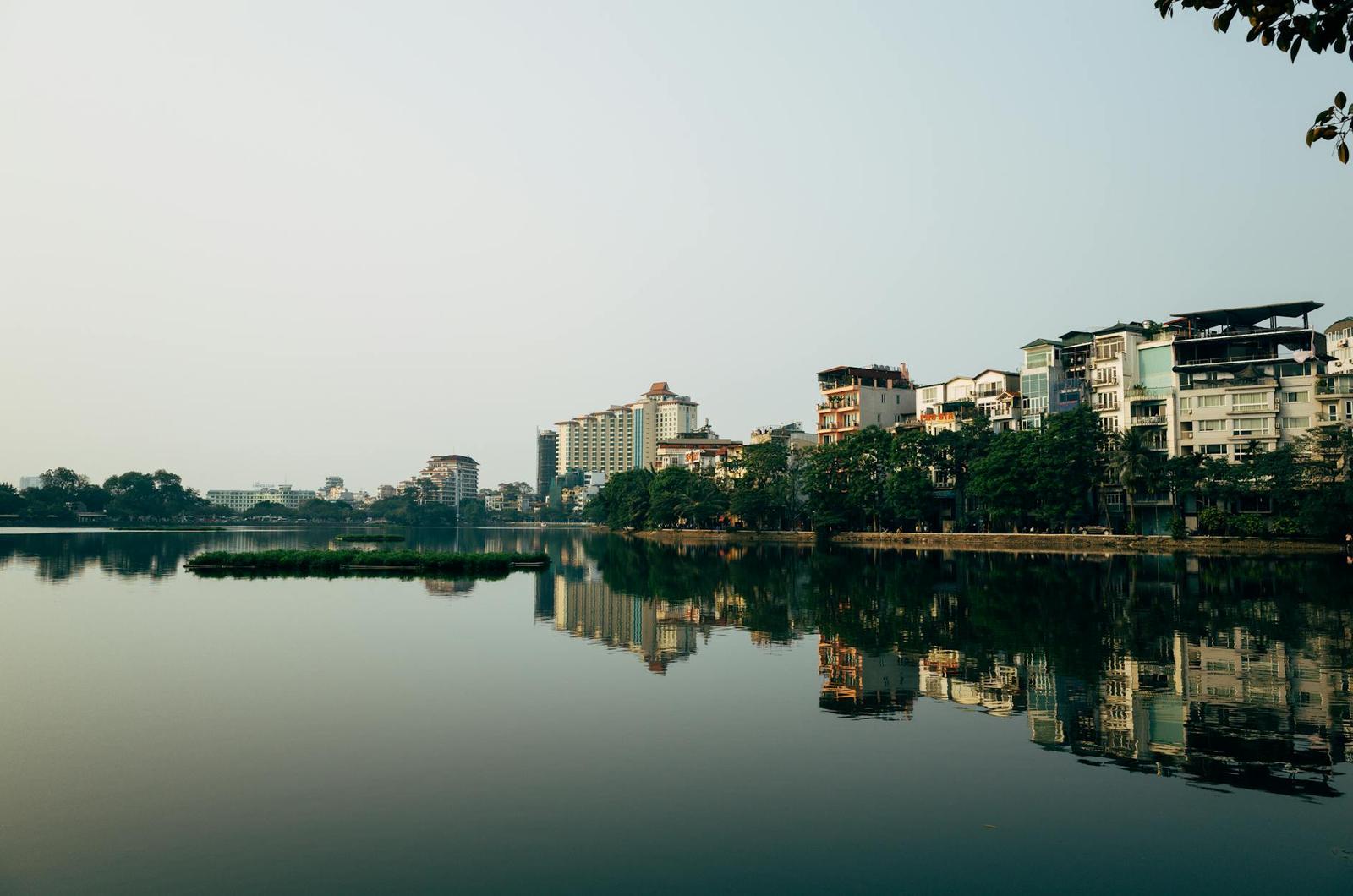 Calm city lake mirroring apartment towers and waterfront trees