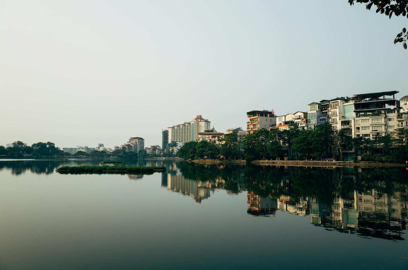 Calm city lake mirroring apartment towers and waterfront trees