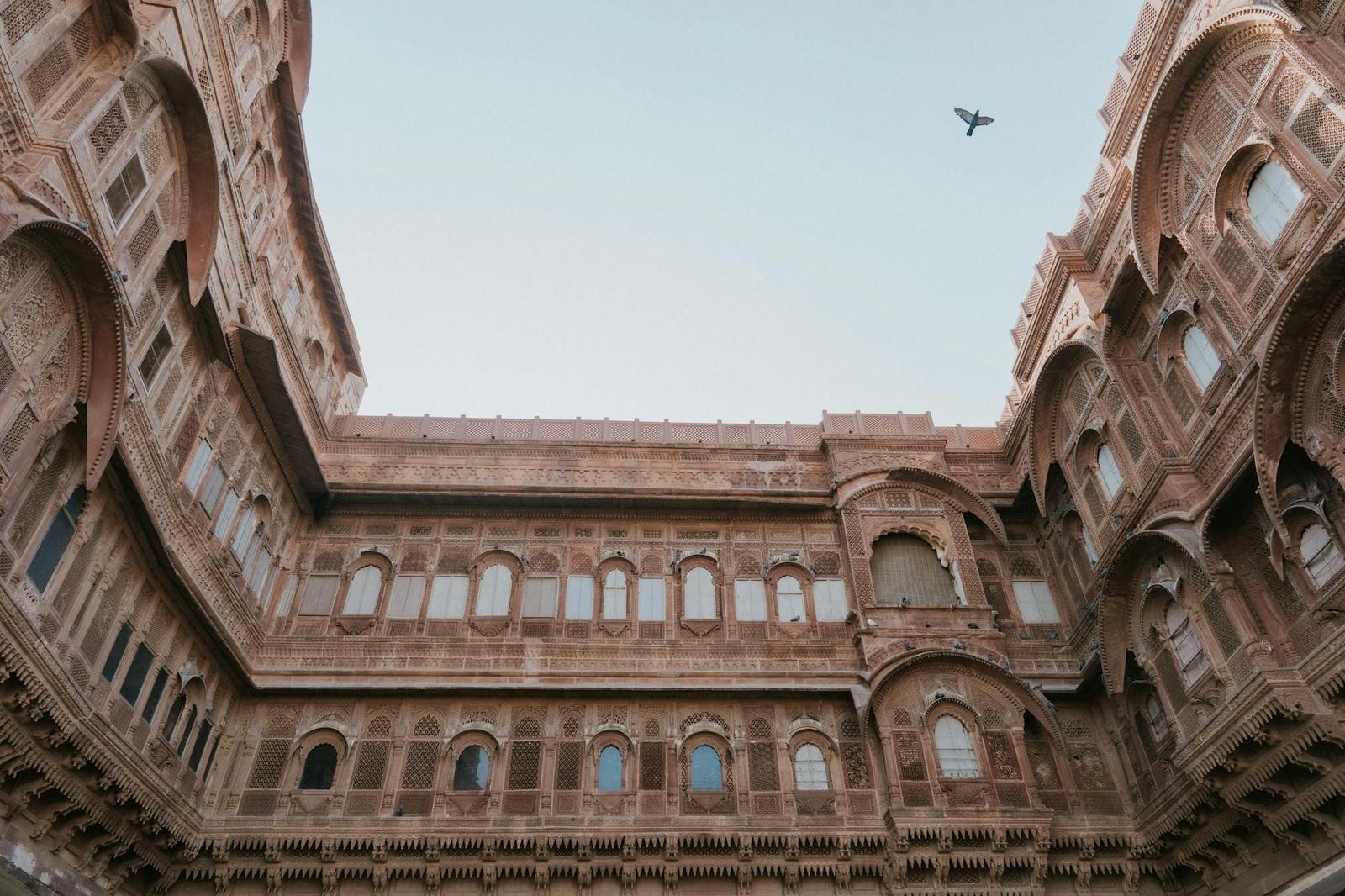 Sandstone fort walls rising around a courtyard with a bird overhead