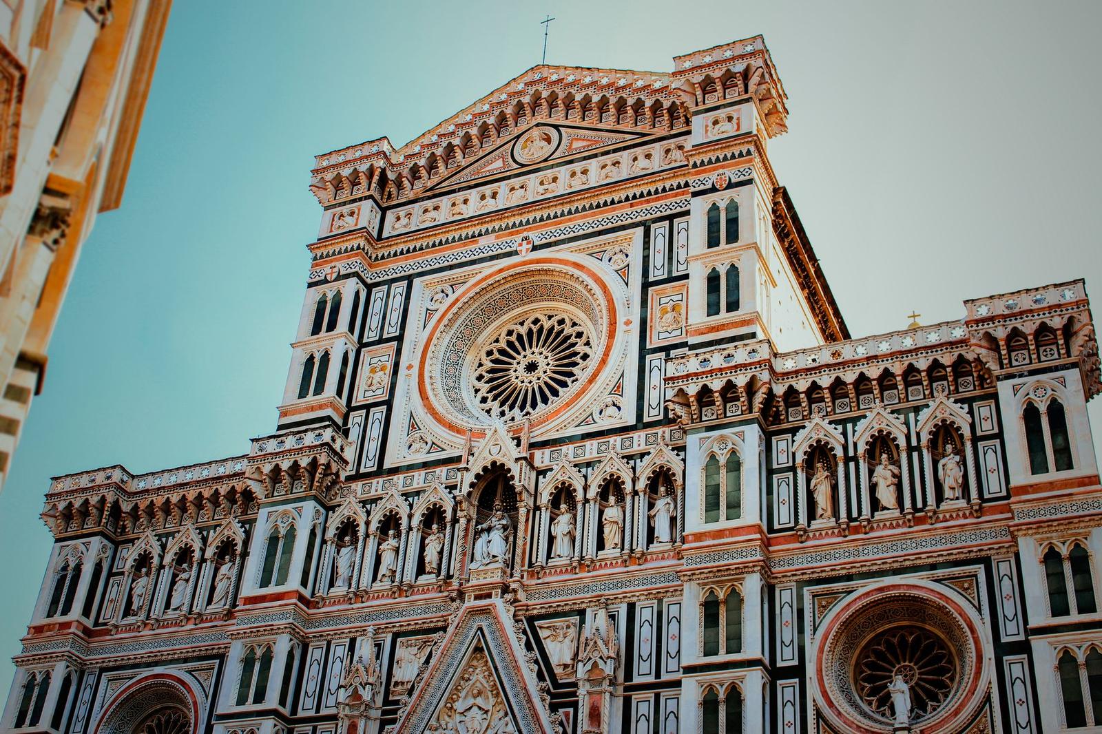 Ornate marble cathedral facade with a rose window seen from below