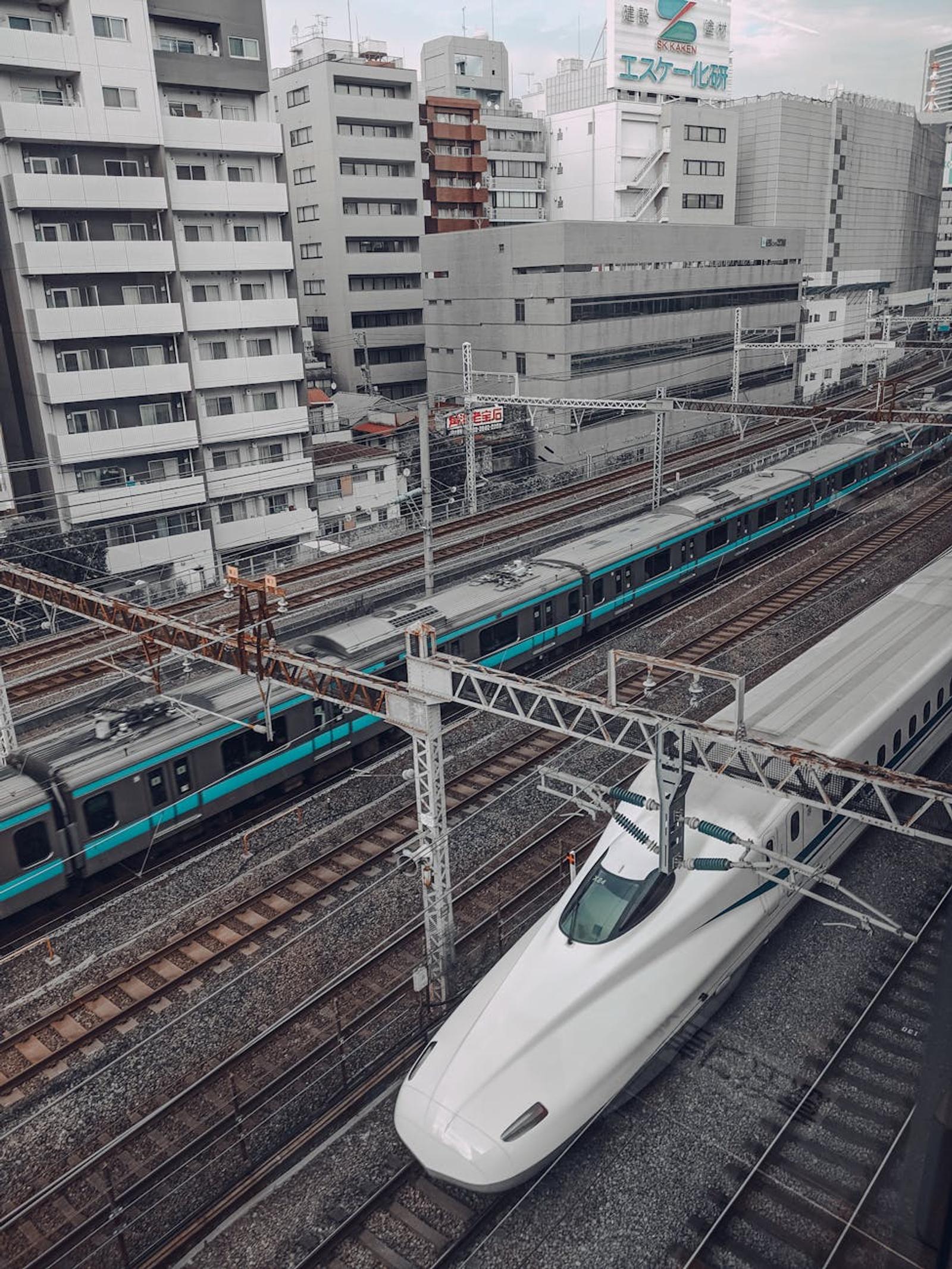 Bullet train easing into a station surrounded by city apartment blocks