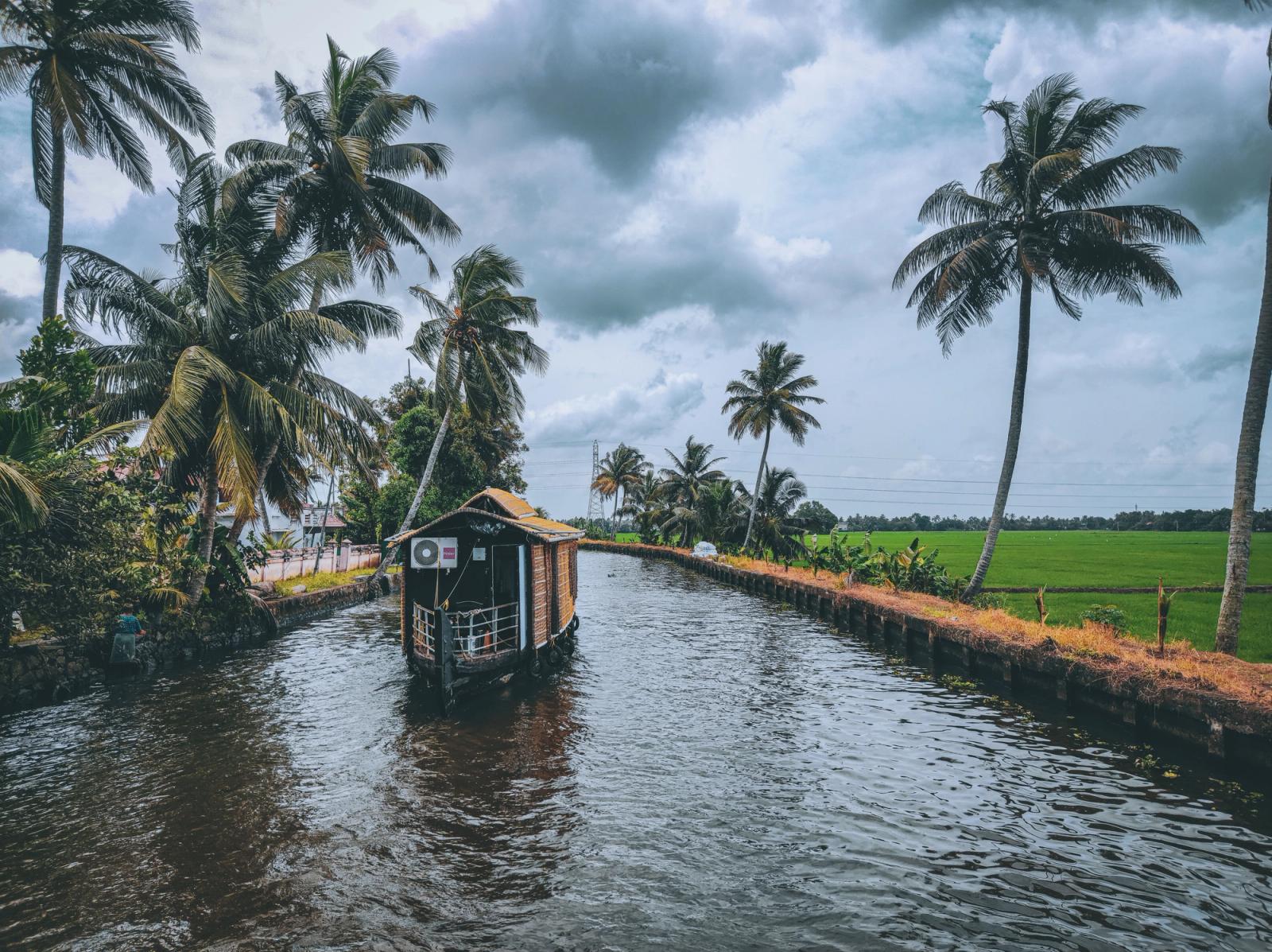 Scenic houseboat on a tranquil canal surrounded by lush palm trees in Kerala, India