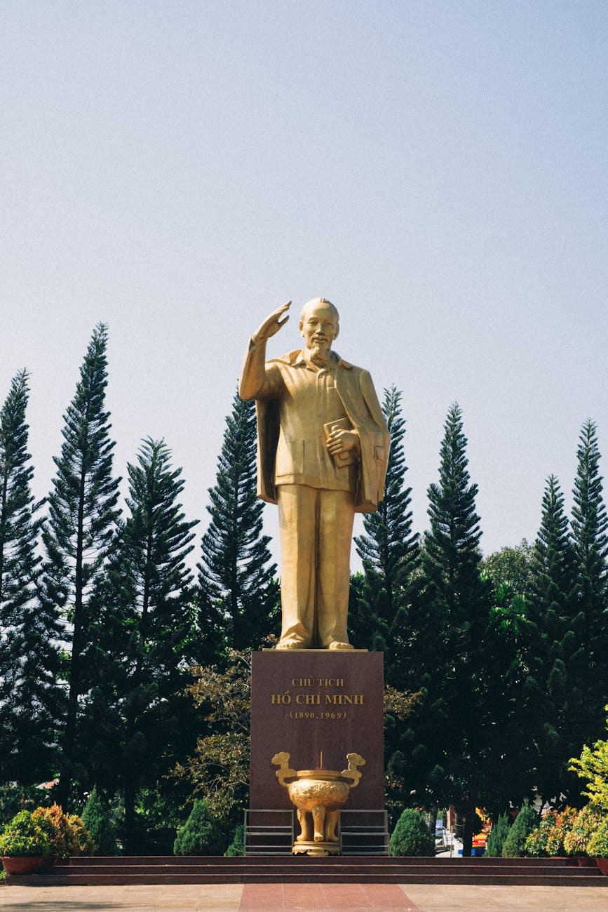 Golden statue of a saluting historic leader among tall pine trees