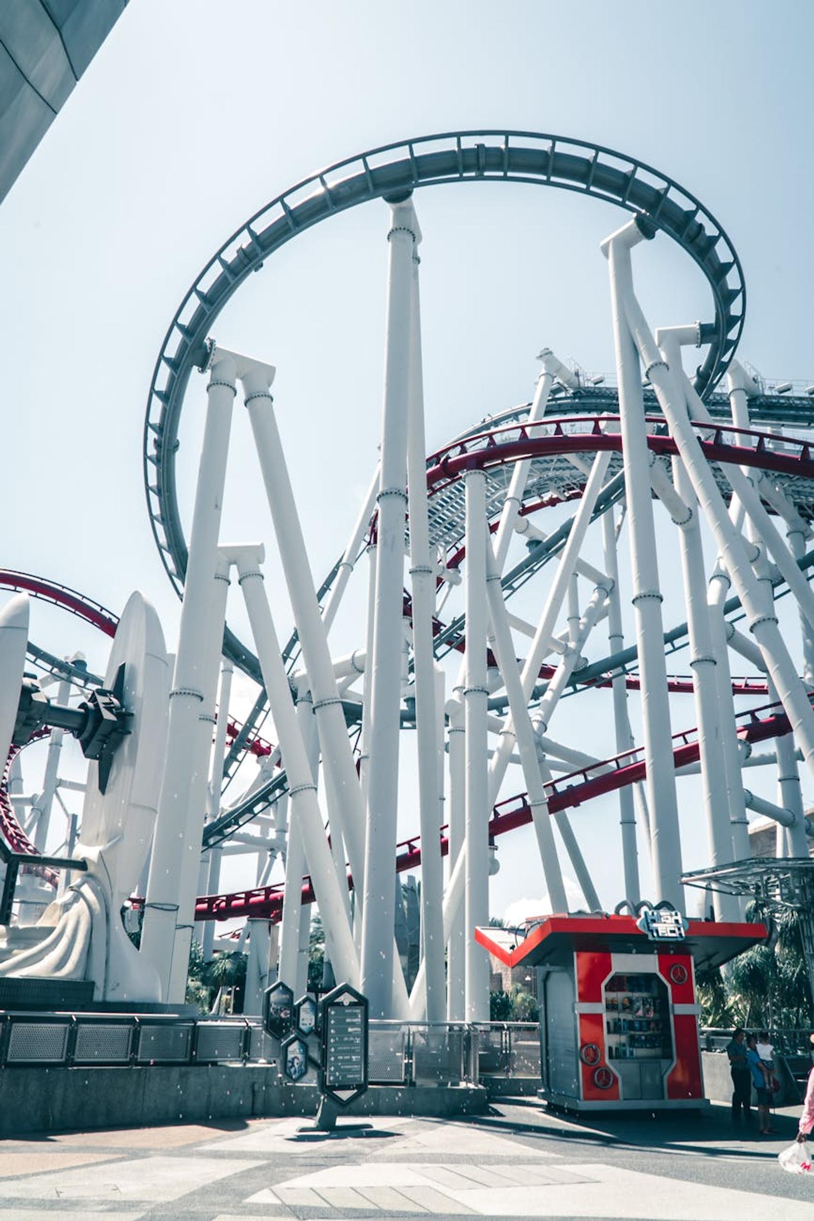 Looping steel roller coaster track rising against a bright sky at a theme park