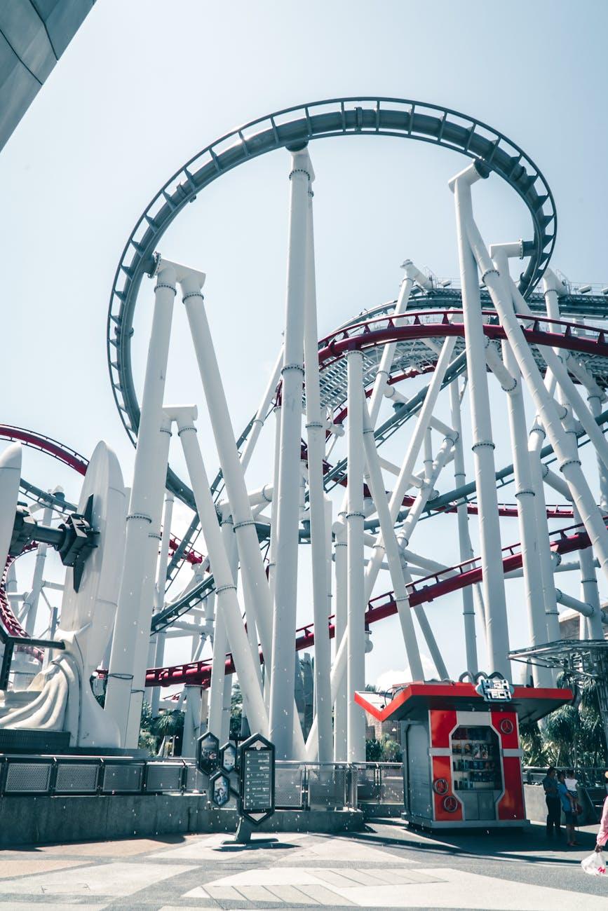 Looping steel roller coaster track rising against a bright sky at a theme park