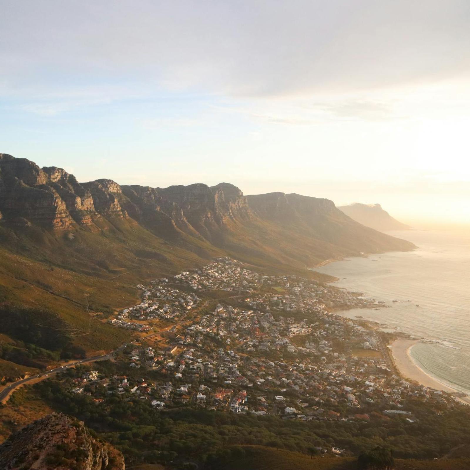 Aerial view of a mountainside coastal town glowing at sunset