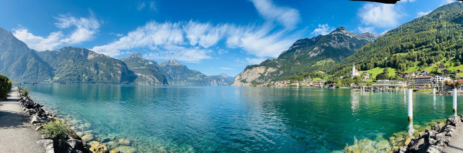 Stunning panoramic view of a lake with mountain backdrop under a bright sky in Flüelen, Switzerland