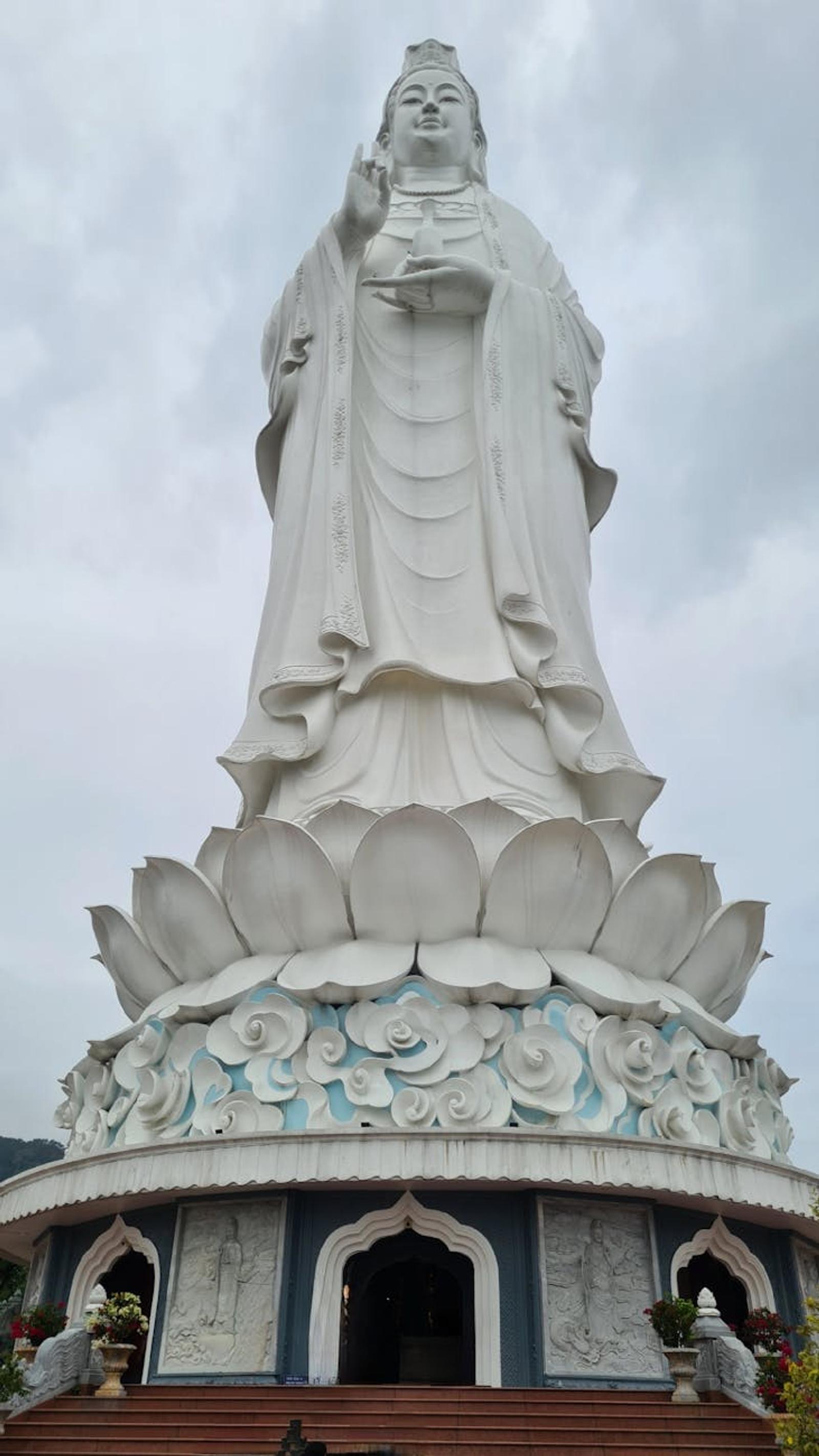 Tall white bodhisattva statue standing on a lotus pedestal