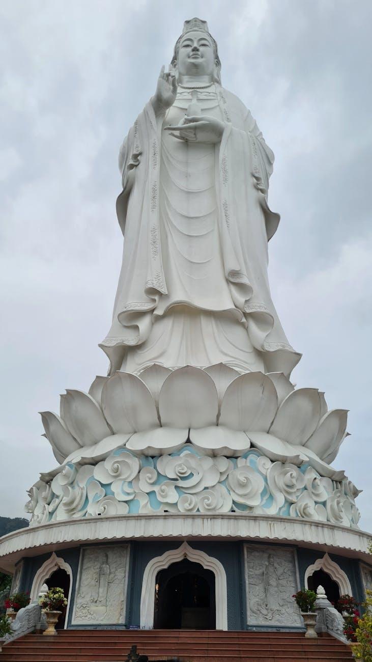 Tall white bodhisattva statue standing on a lotus pedestal